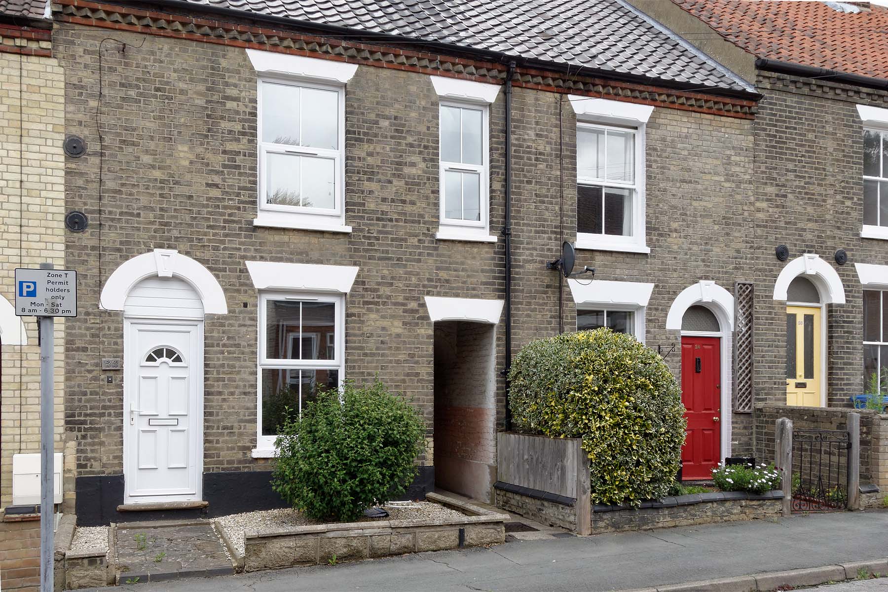 Grey brick terraced house with white front door