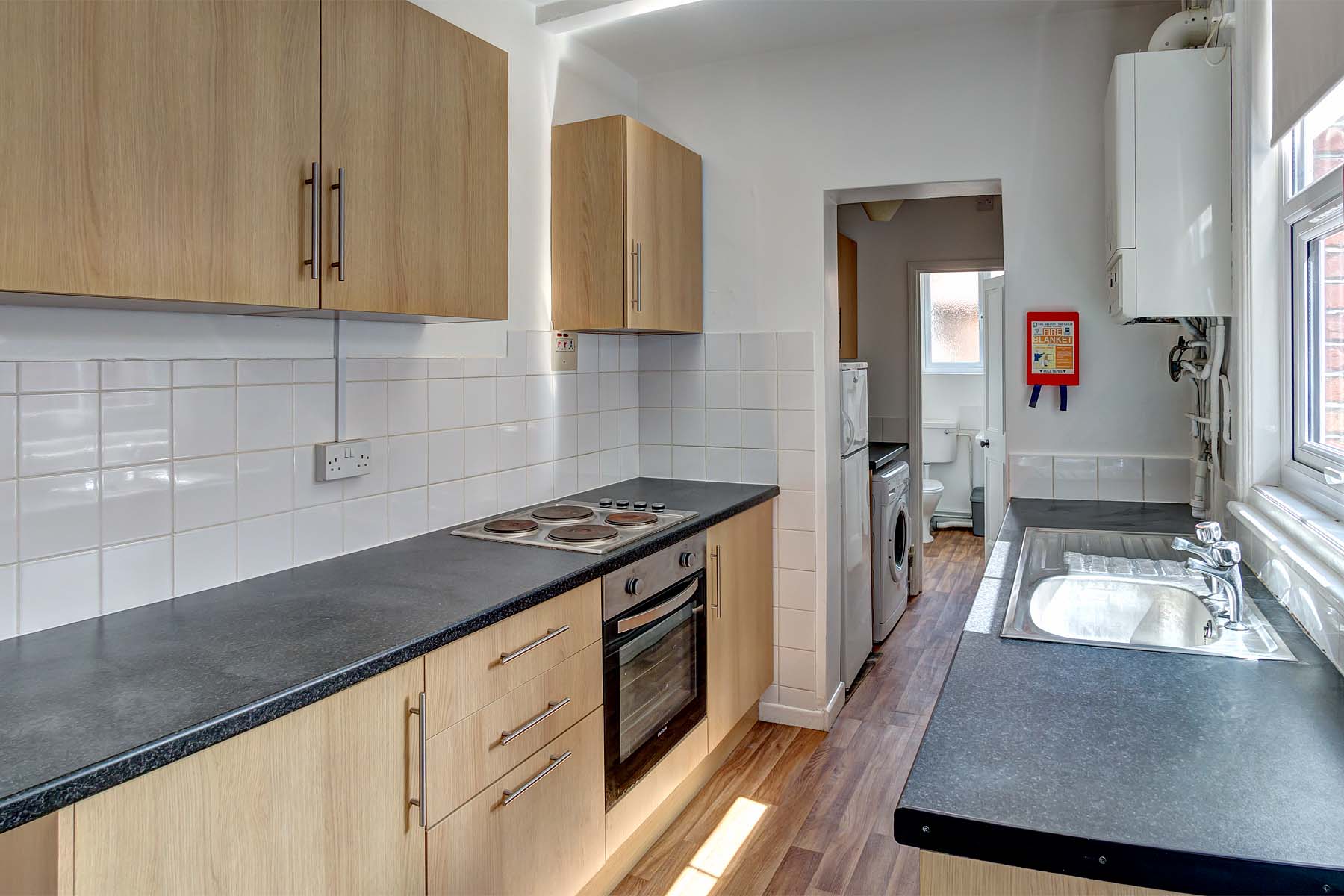 Modern galley kitchen with wood effect cabinets and black worktop