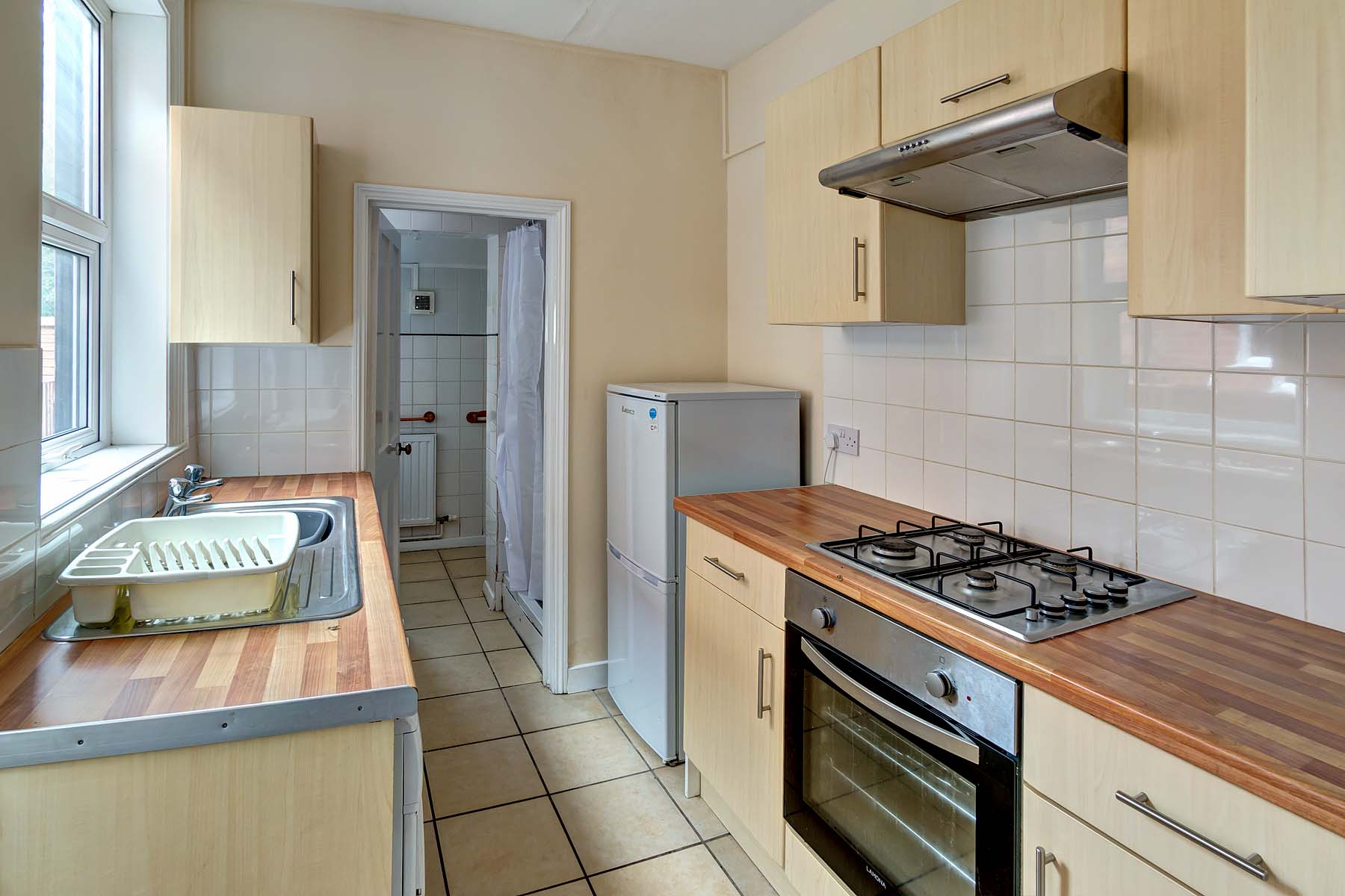Galley kitchen with cream cabinets and large appliances.