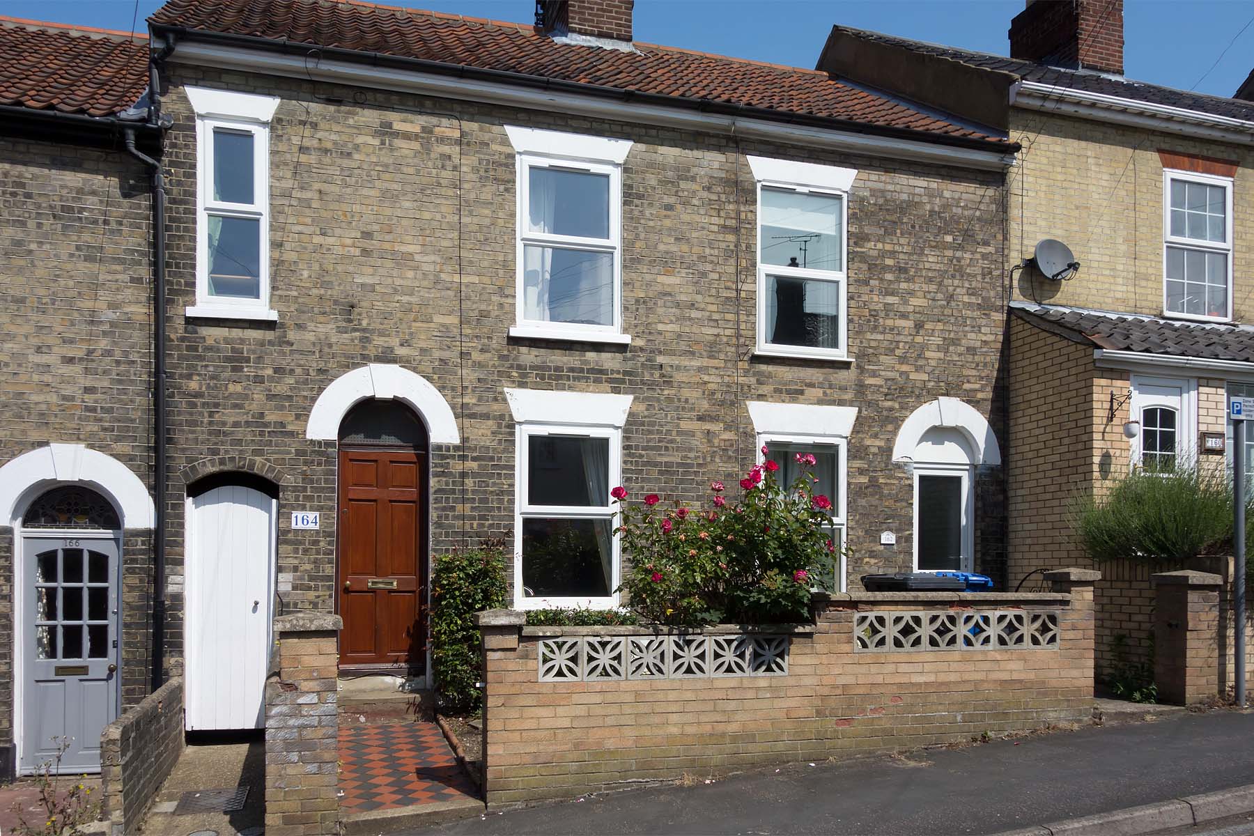 Brick terraced house with red door.