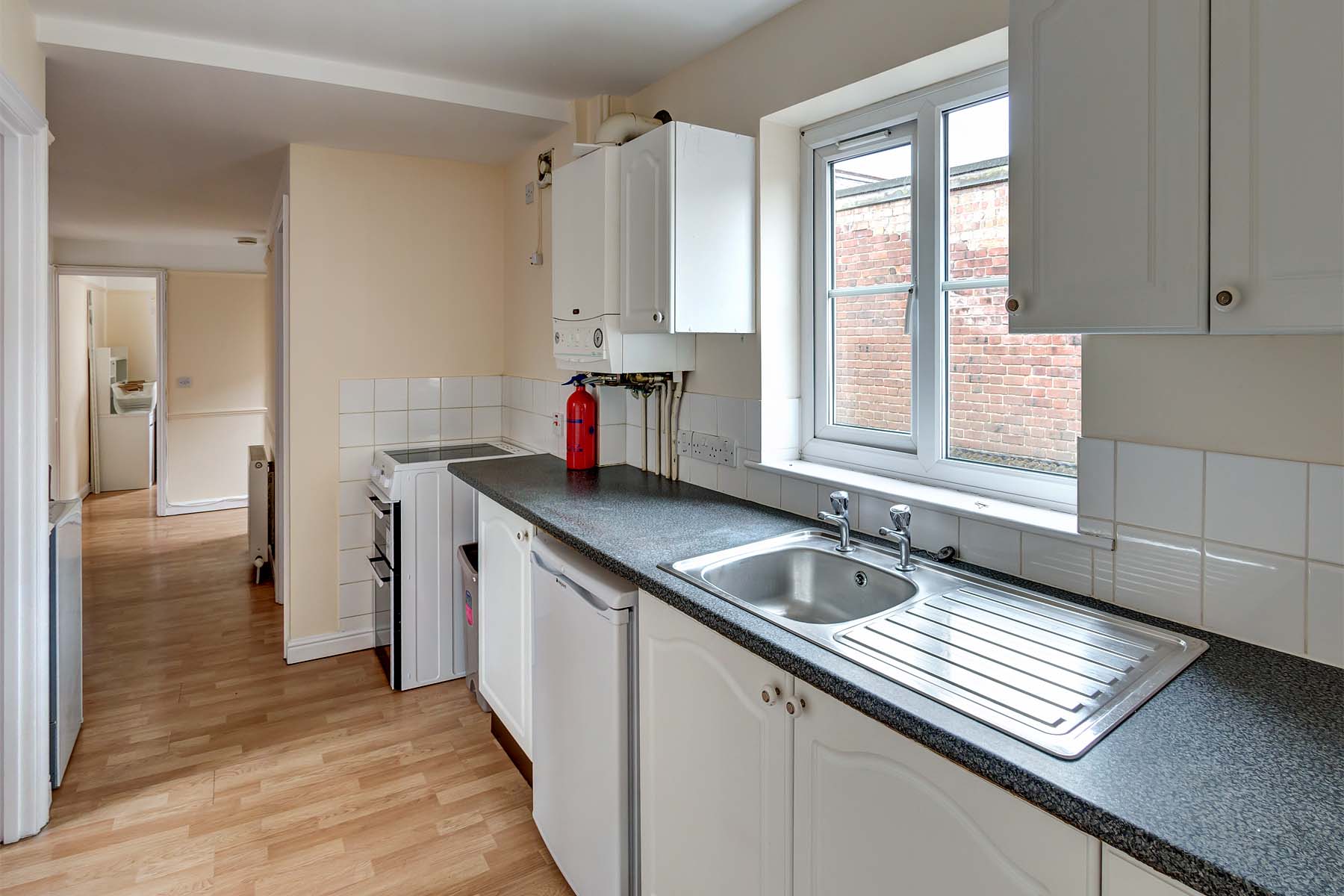 Fitted kitchen with white cupboards and black grain worktop.