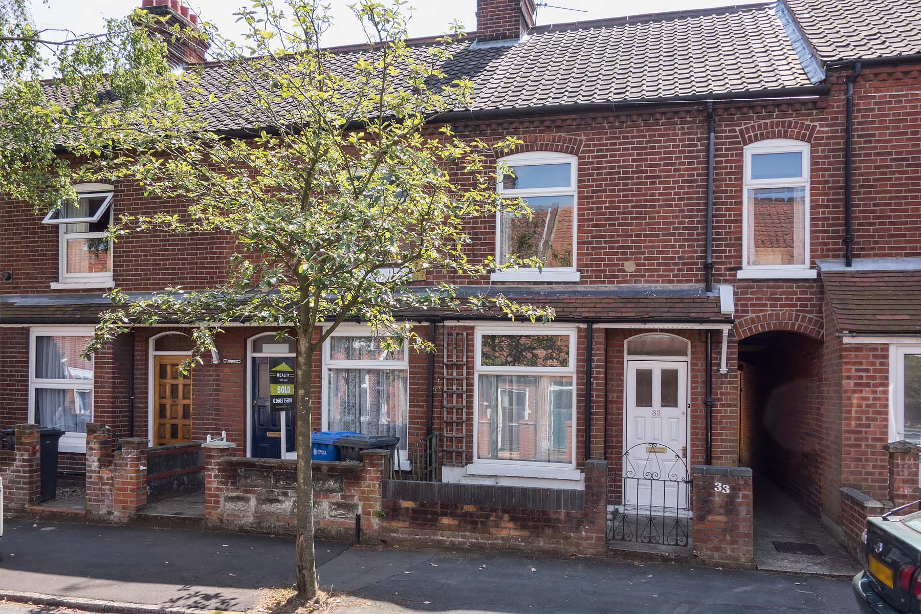 Red brick terraced house on tree lined street
