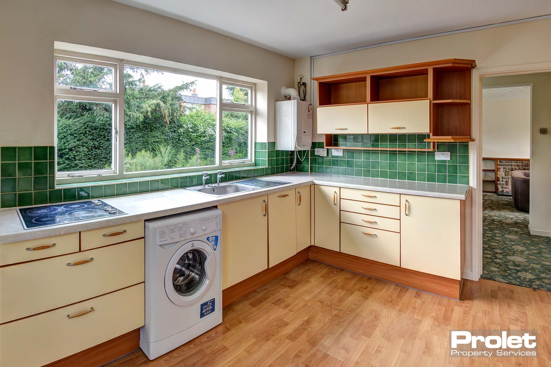 Large kitchen with laminate floor, tiled backsplash, and cream cabinets