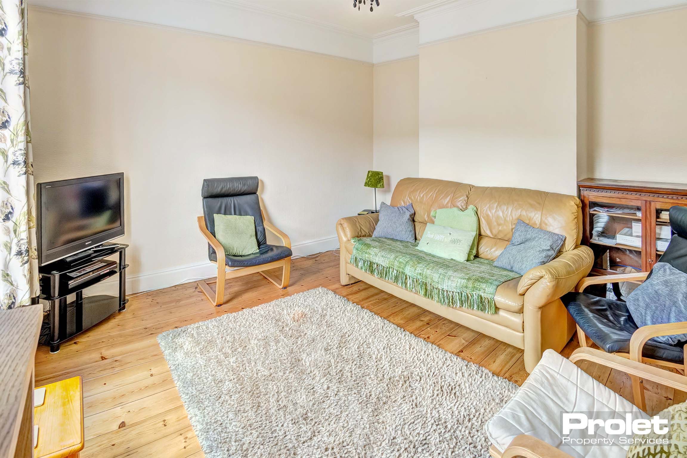 Living room with wooden floor, sofa, and armchairs