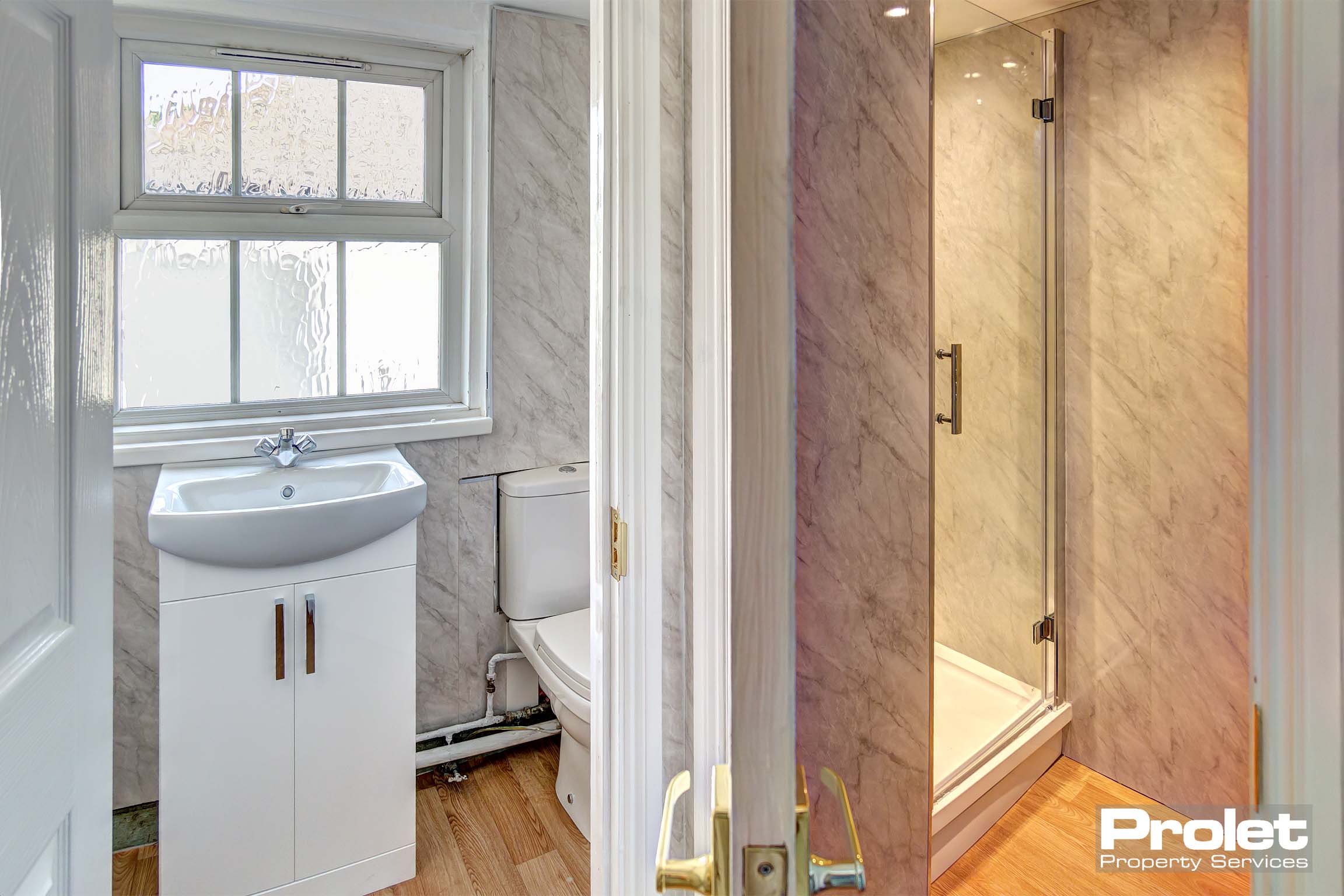 Bathroom with toilet, sink, and shower cubicle.