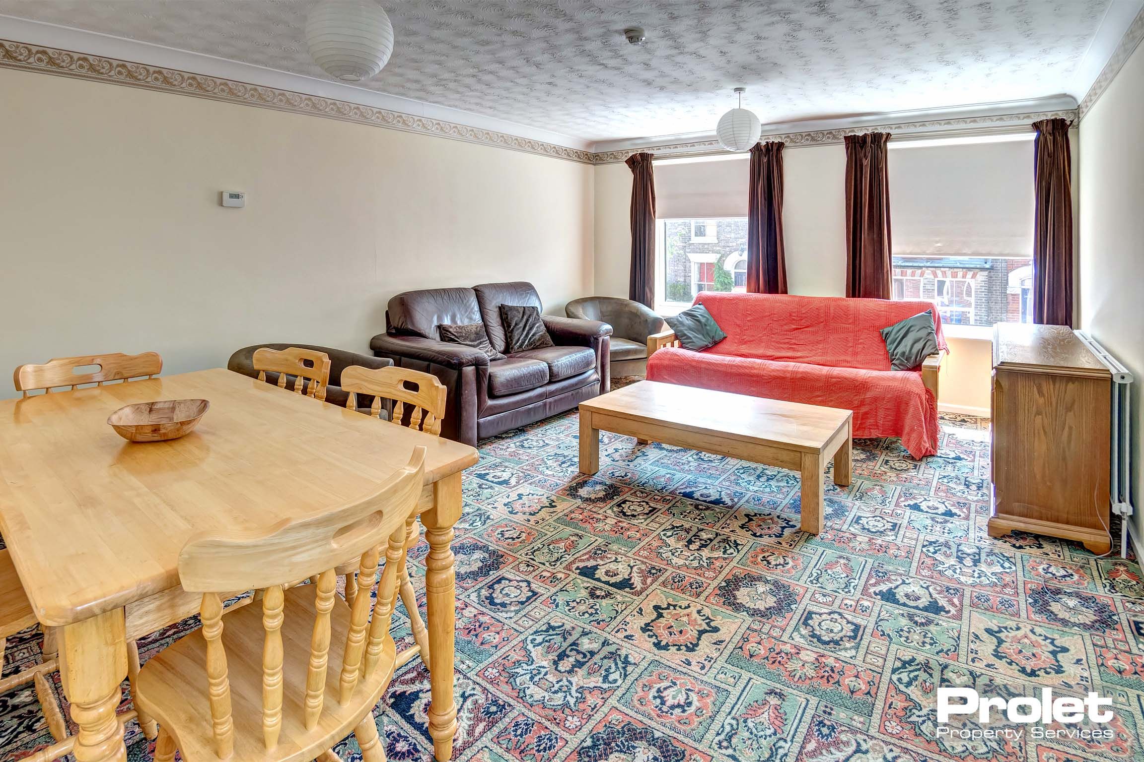 Large living and dining area with patterned carpet, dining set, and sofas