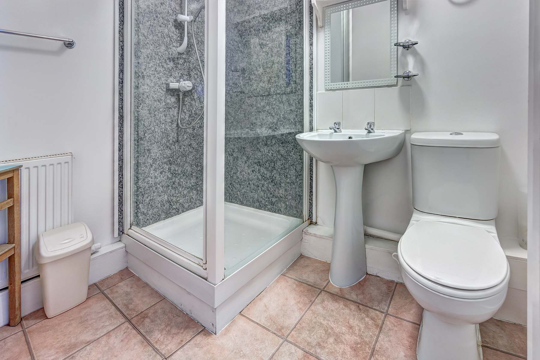 Shower room with white toilet and sink and glass walk in shower.