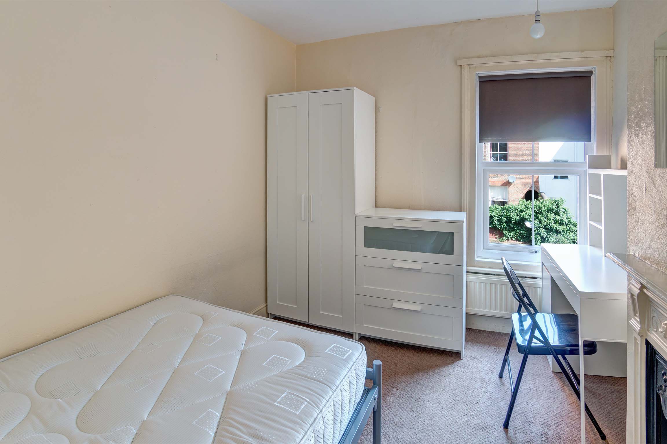 Bedroom with white wardrobe and chest of drawers. Desk and chair.