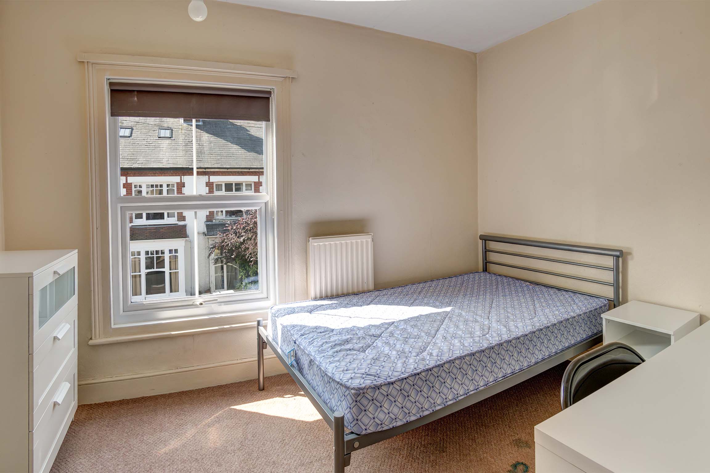 Bedroom with double bed, chest of drawers and desk with a chair