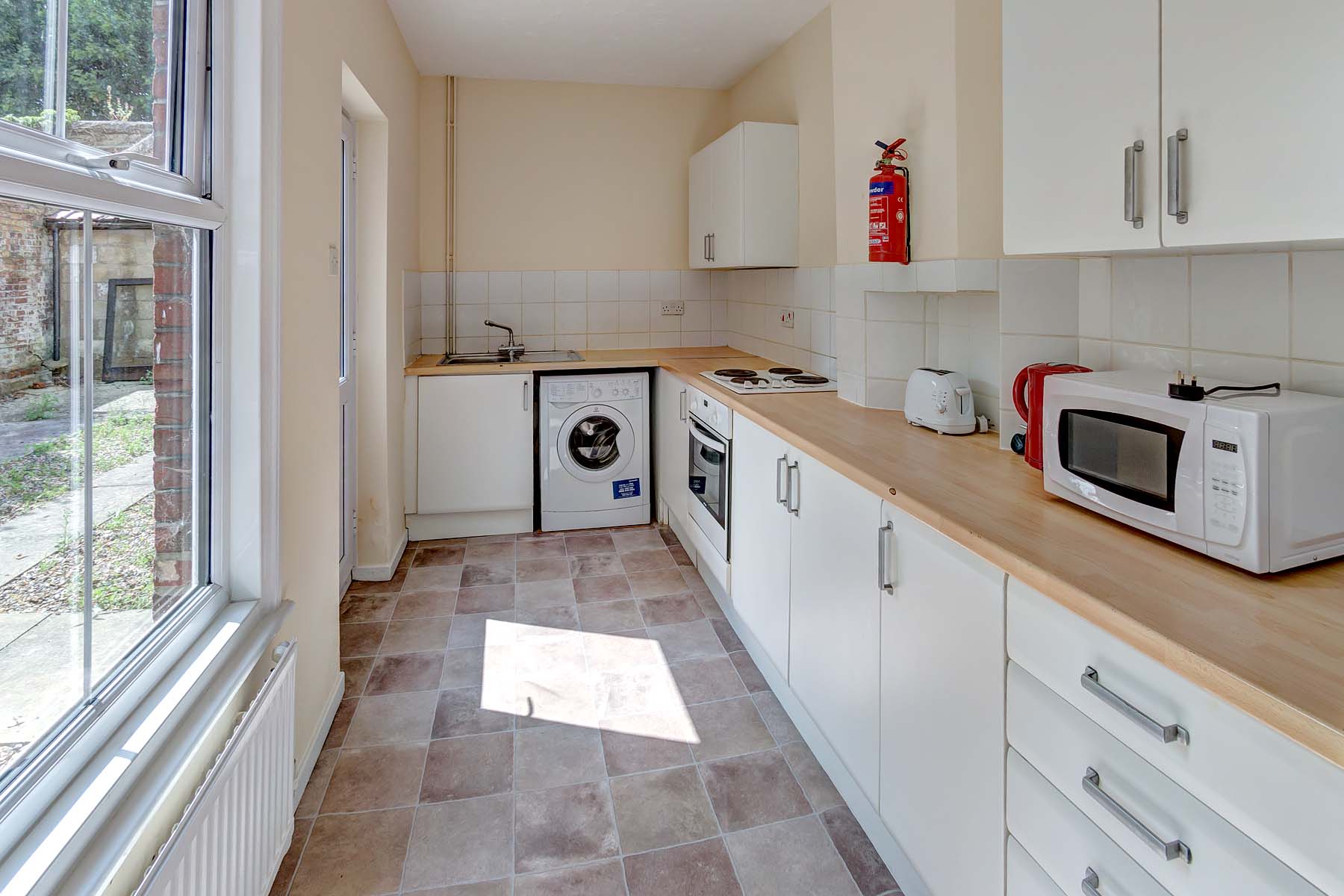 Long galley kitchen with white units and wood effect worktop