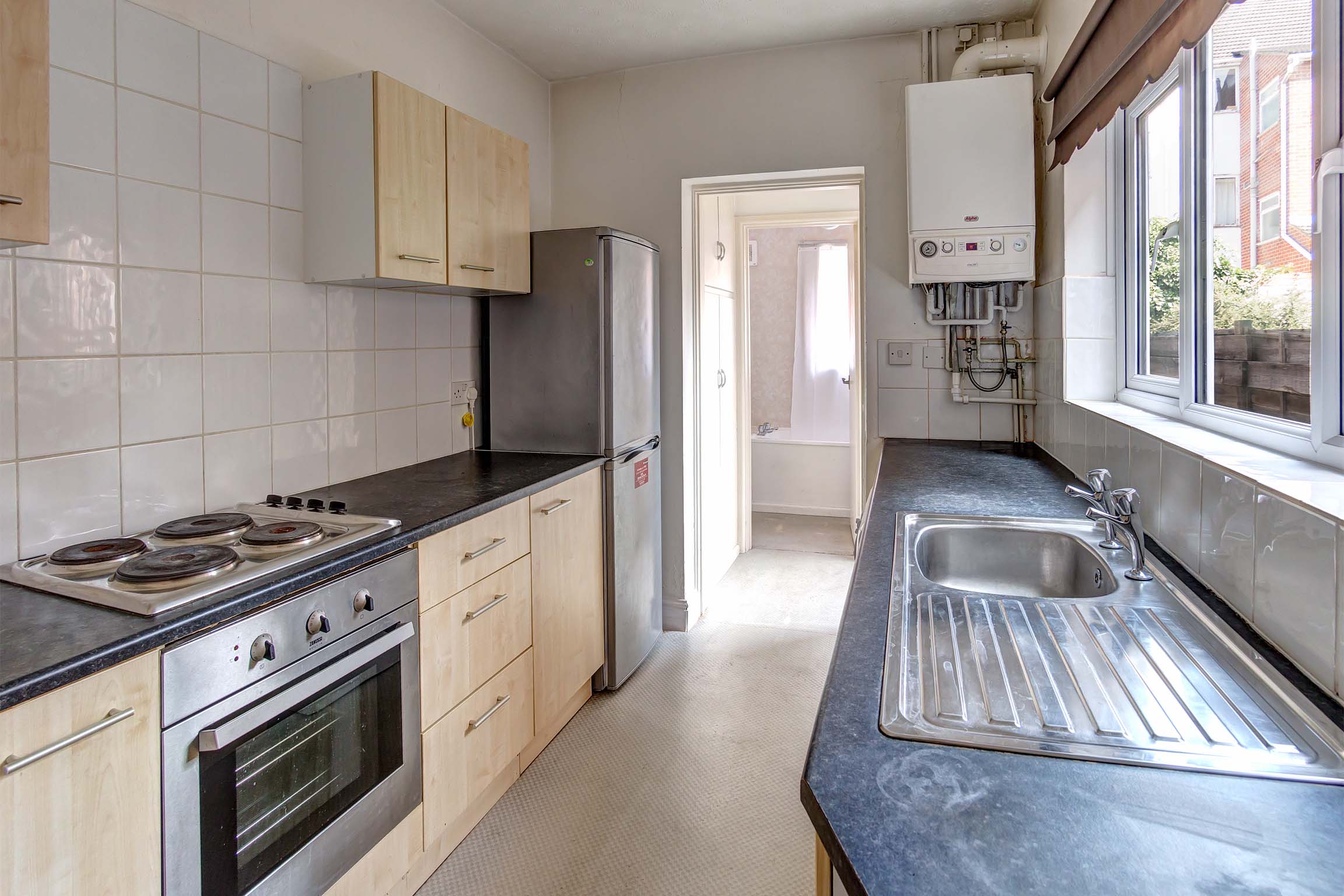 Wooden galley style fitted kitchen with black worktop.