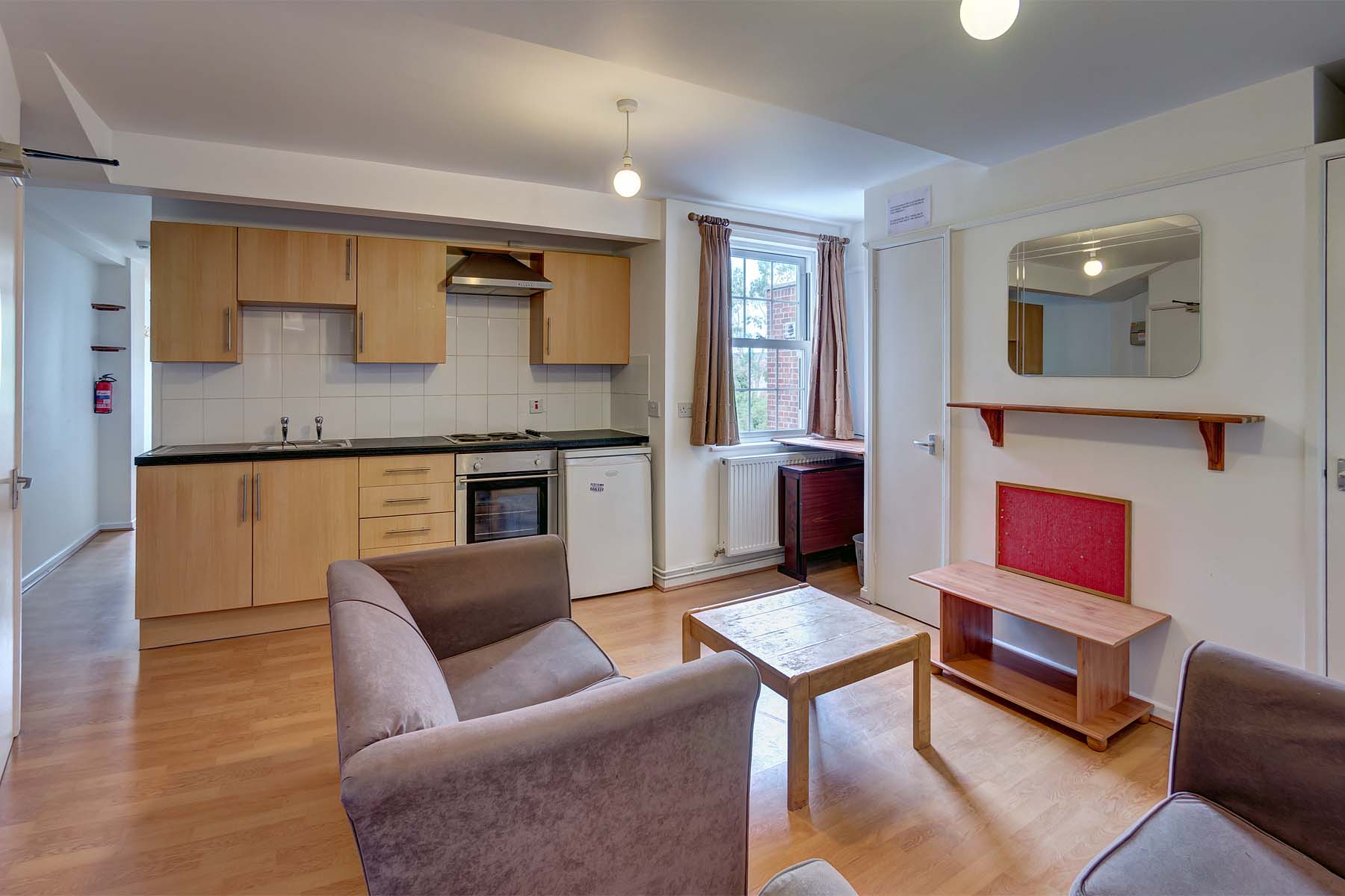 Fitted wooden kitchen, wooden flooring, lounge area with two sofas and a centre table.