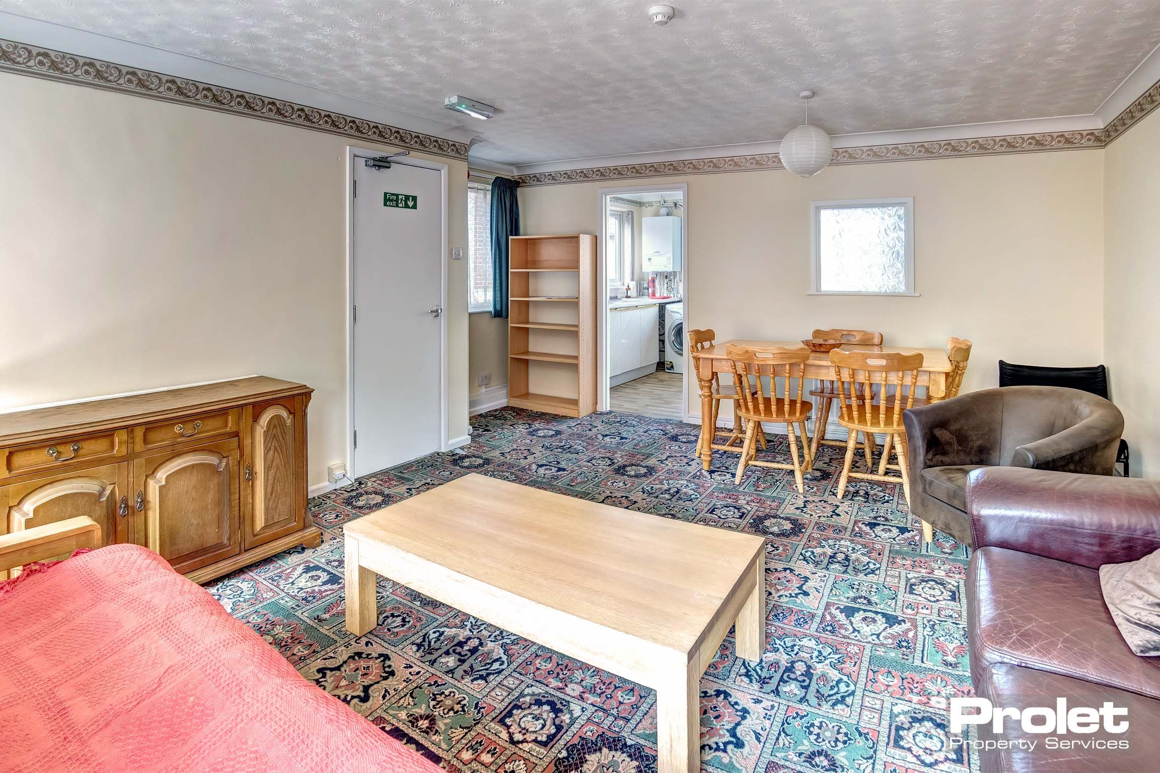 Large living and dining area with patterned carpet, dining set, and sofas