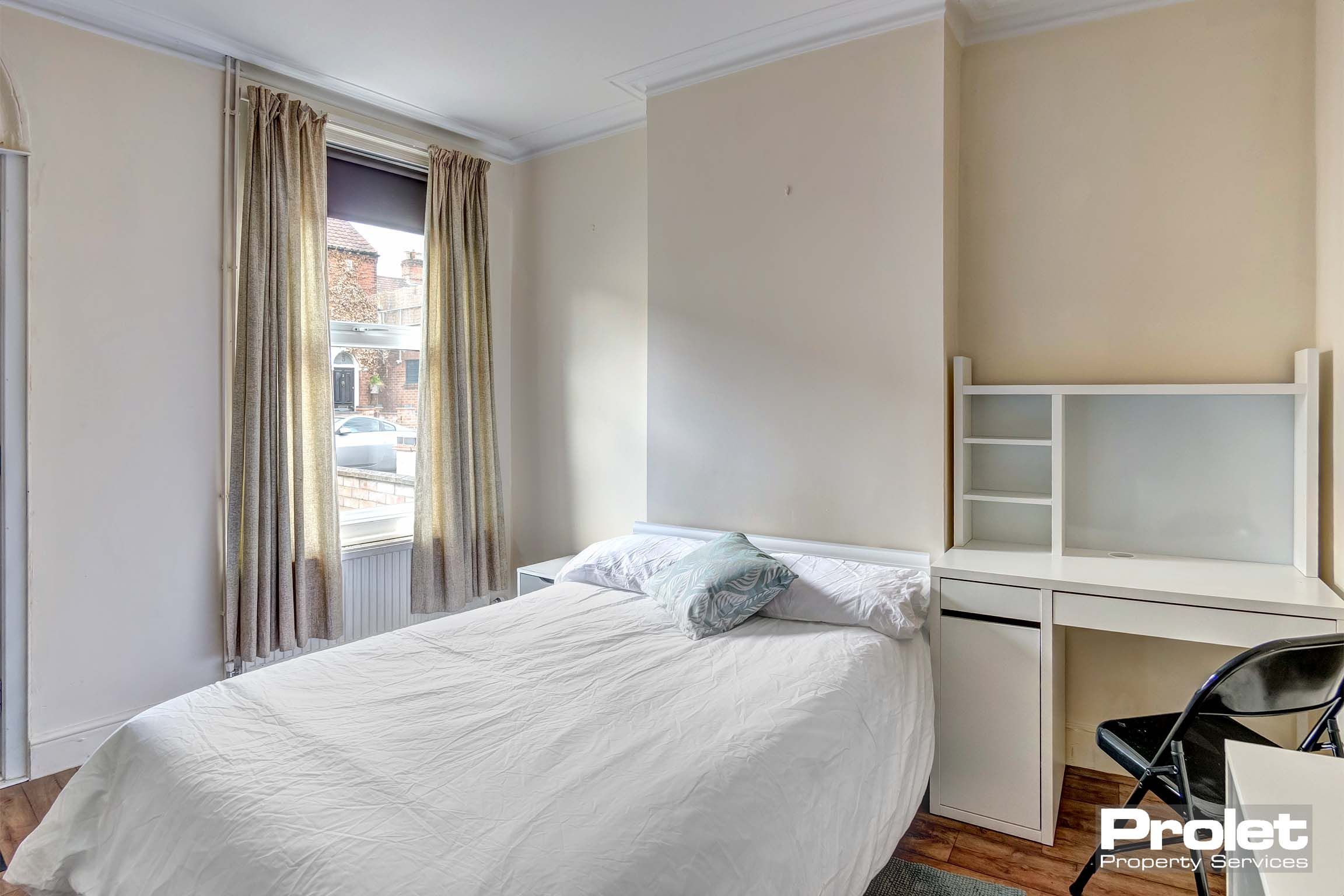 A double bedroom painted with magnolia. A white desk and a double bed and mattress.