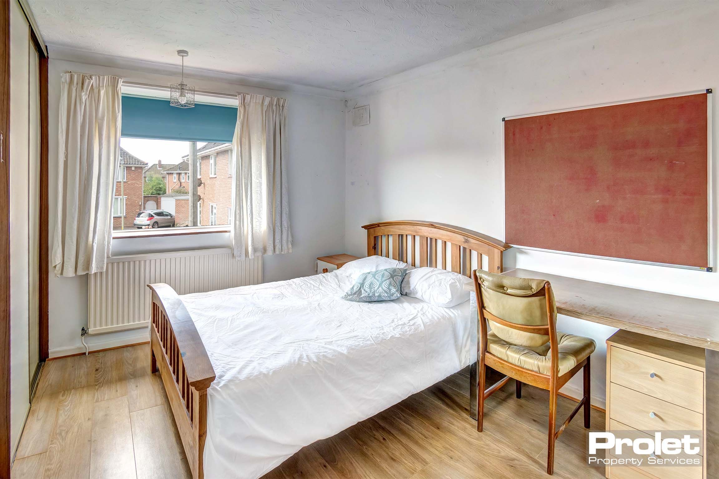Bedroom with wooden bed frame and wooden desk