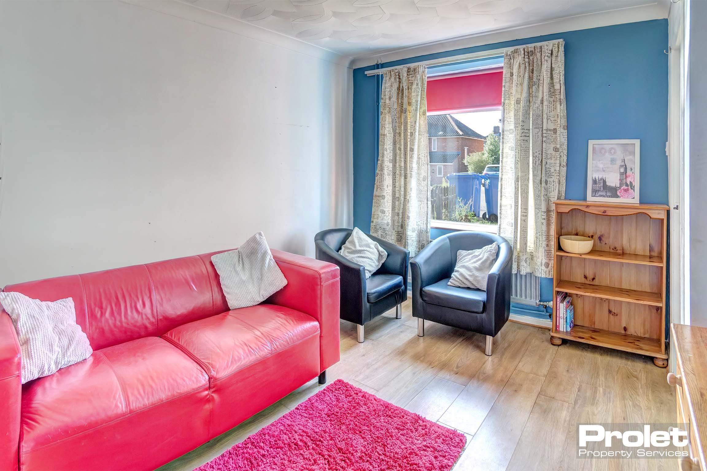 Lounge area painted white and blue with red leather sofa
