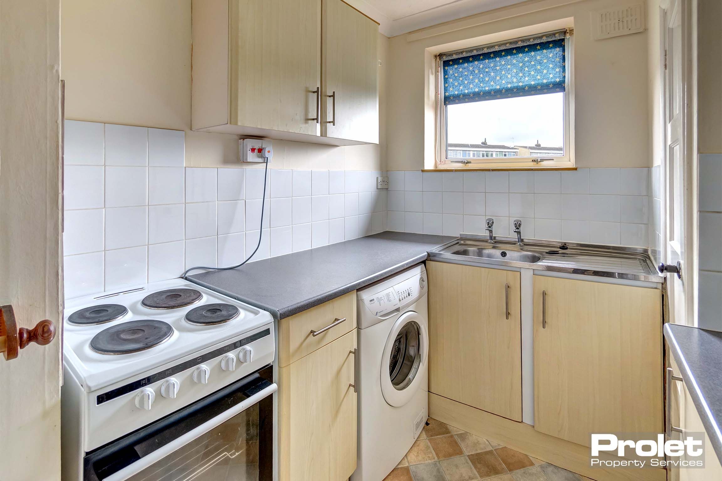 Fitted kitchen with wooden effect cupboards and a dark grey/black worktop.