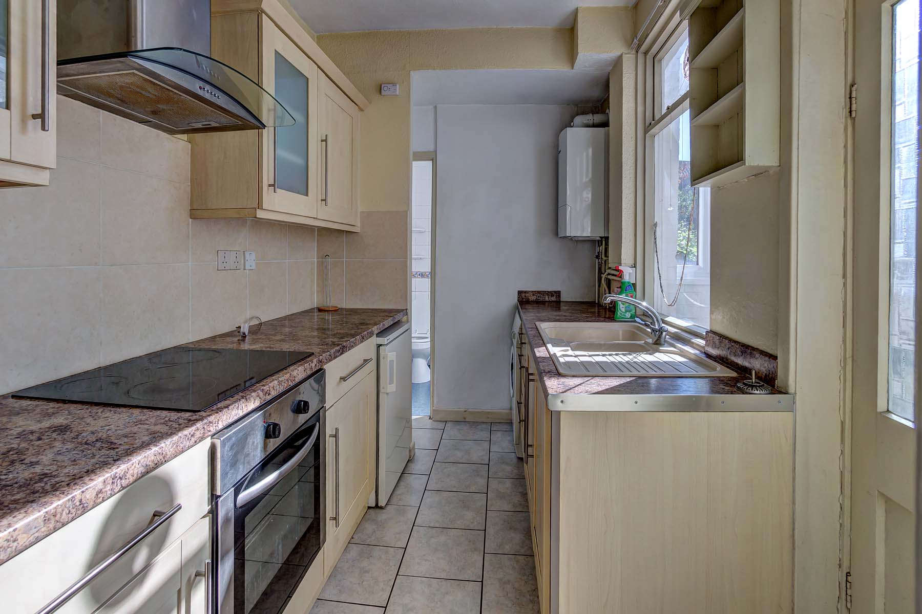Galley style kitchen with wooden effect units and a brown coloured marble worktop.