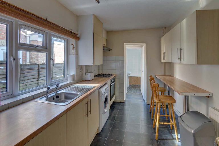 Large galley kitchen with breakfast bar and white goods