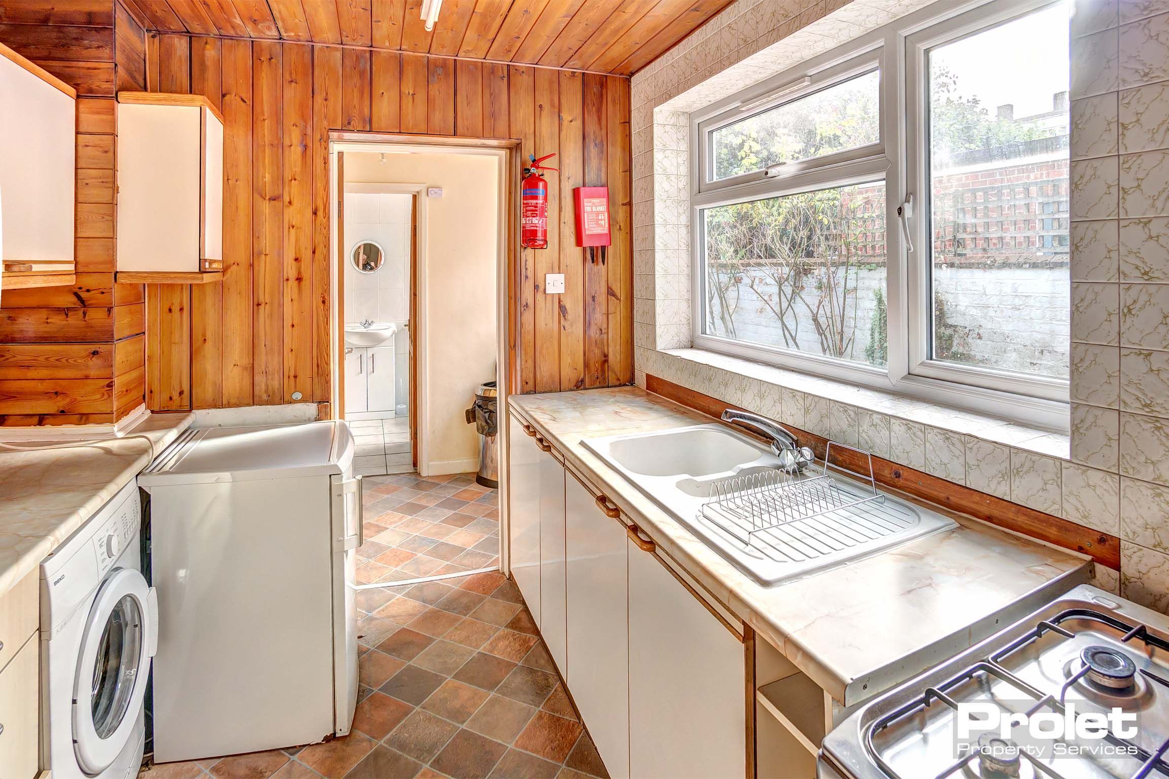 Wood panelled kitchen with white cabinets, and white goods