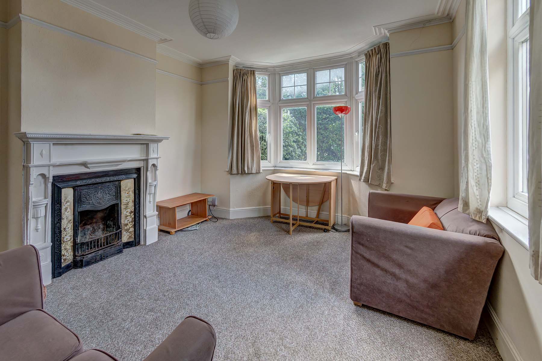 Large living room with bay window, period fireplace, sofa's and dining table