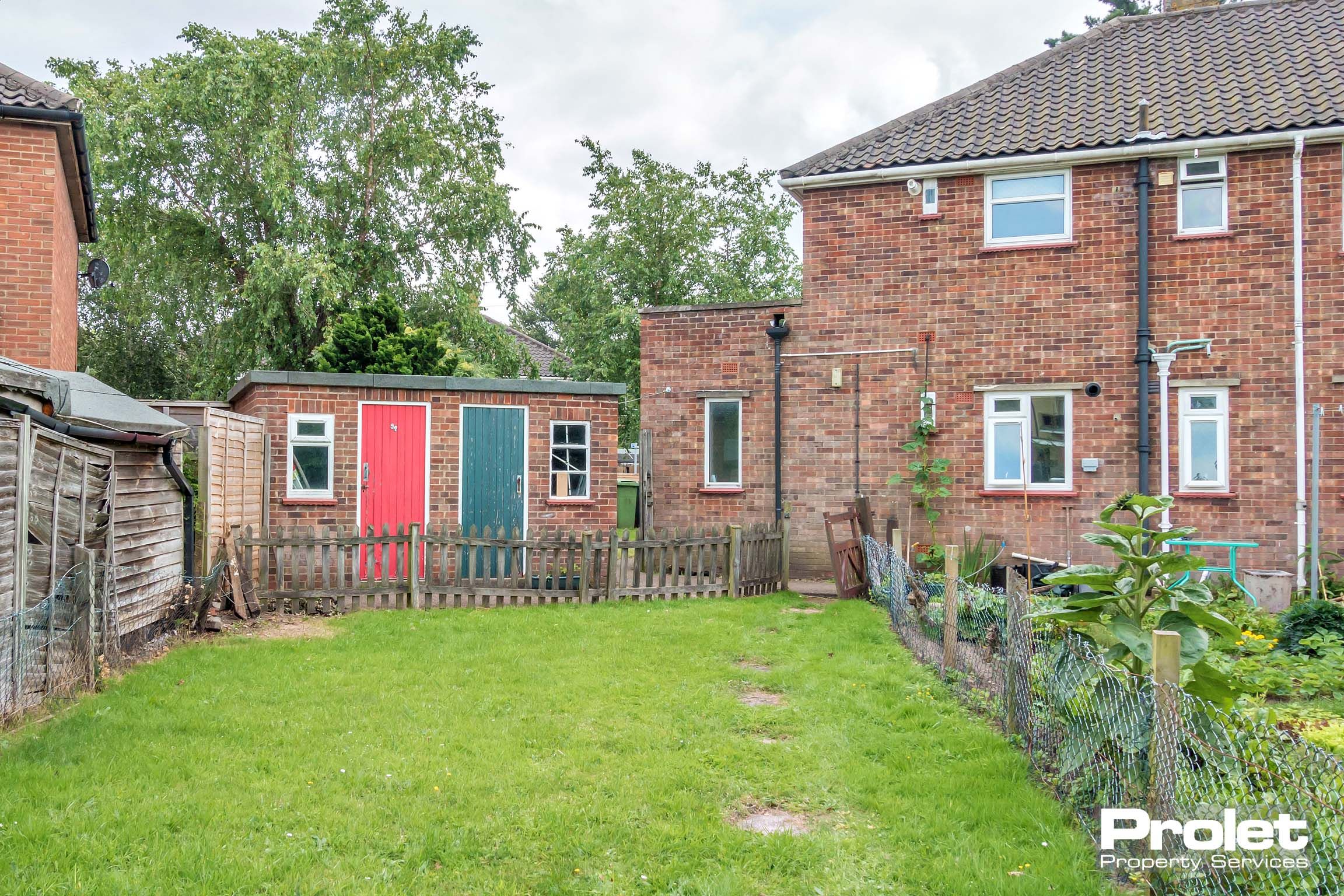 Rear view of the semi detached brick house with grass garden.