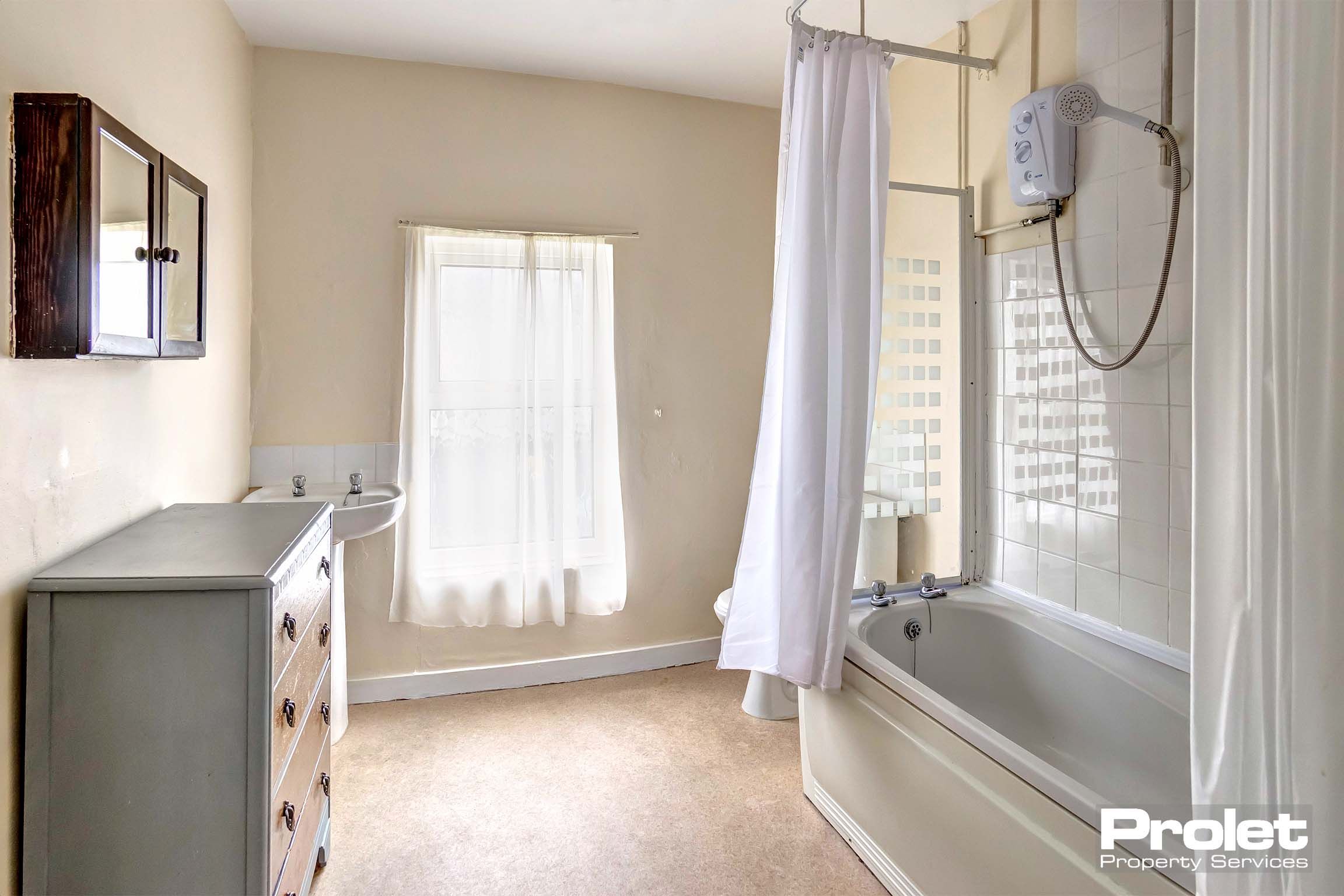 Large bathroom with shower over bath, toilet, and sink