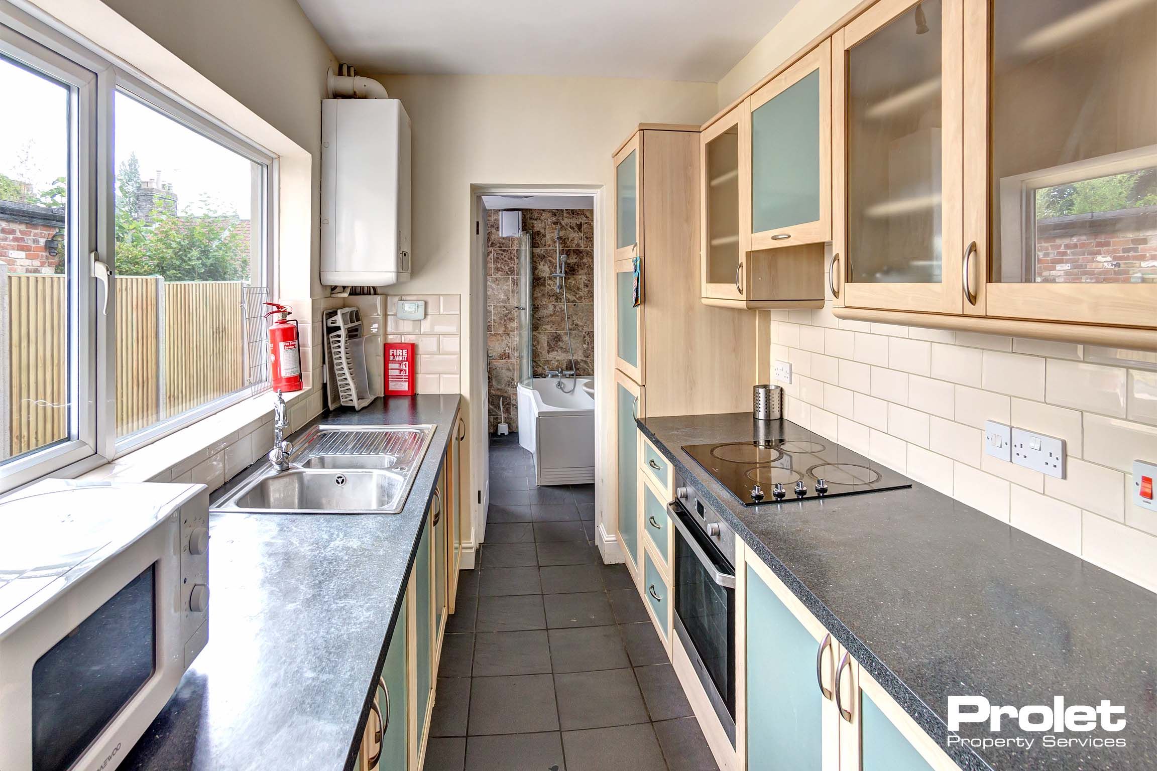 Galley style kitchen with fitted units and a black marble effect worktop.
