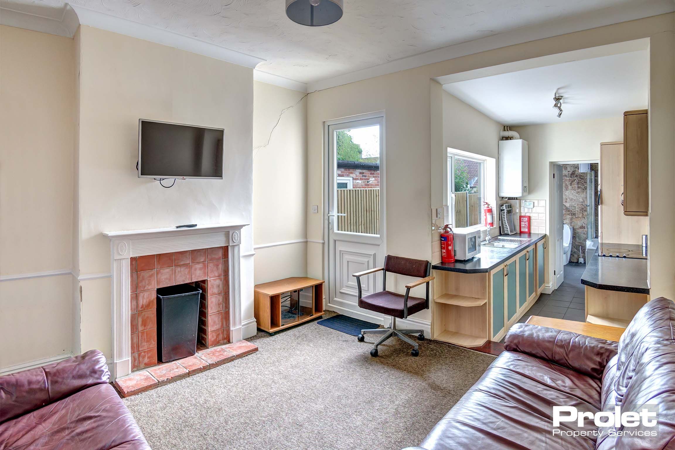 Lounge area with two sofas, a decorative fireplace, and a tv unit.