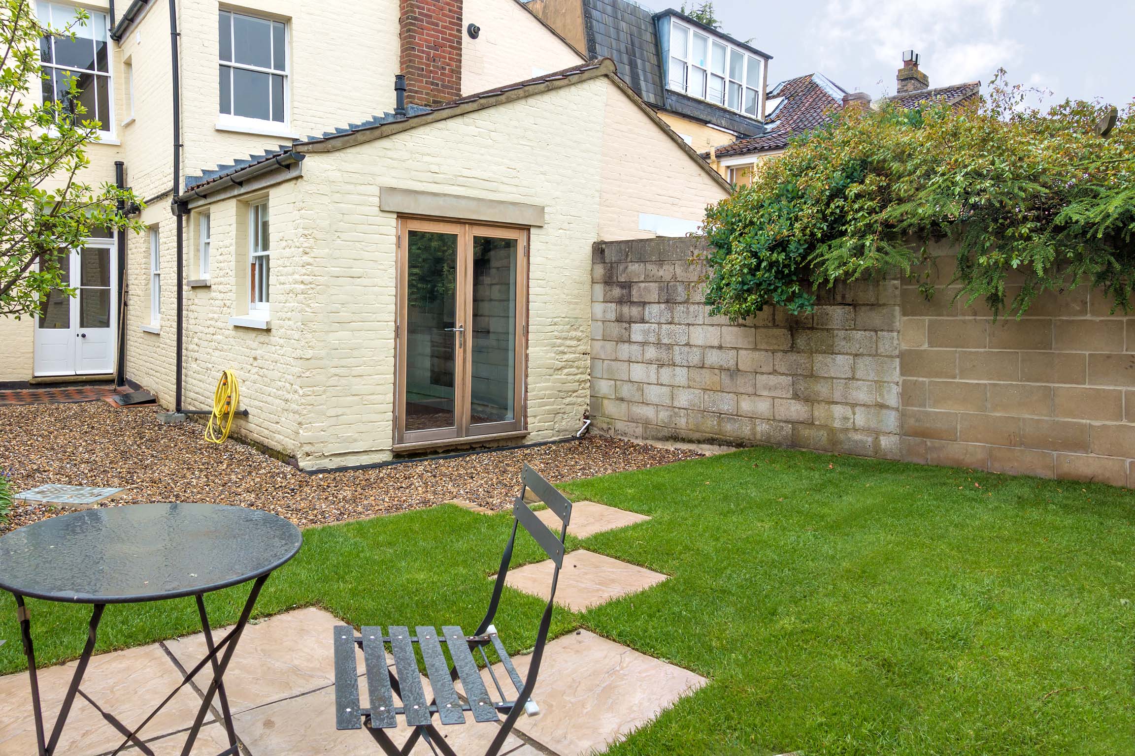 Back garden patio area, laid to lawn, with view of the rear of the house