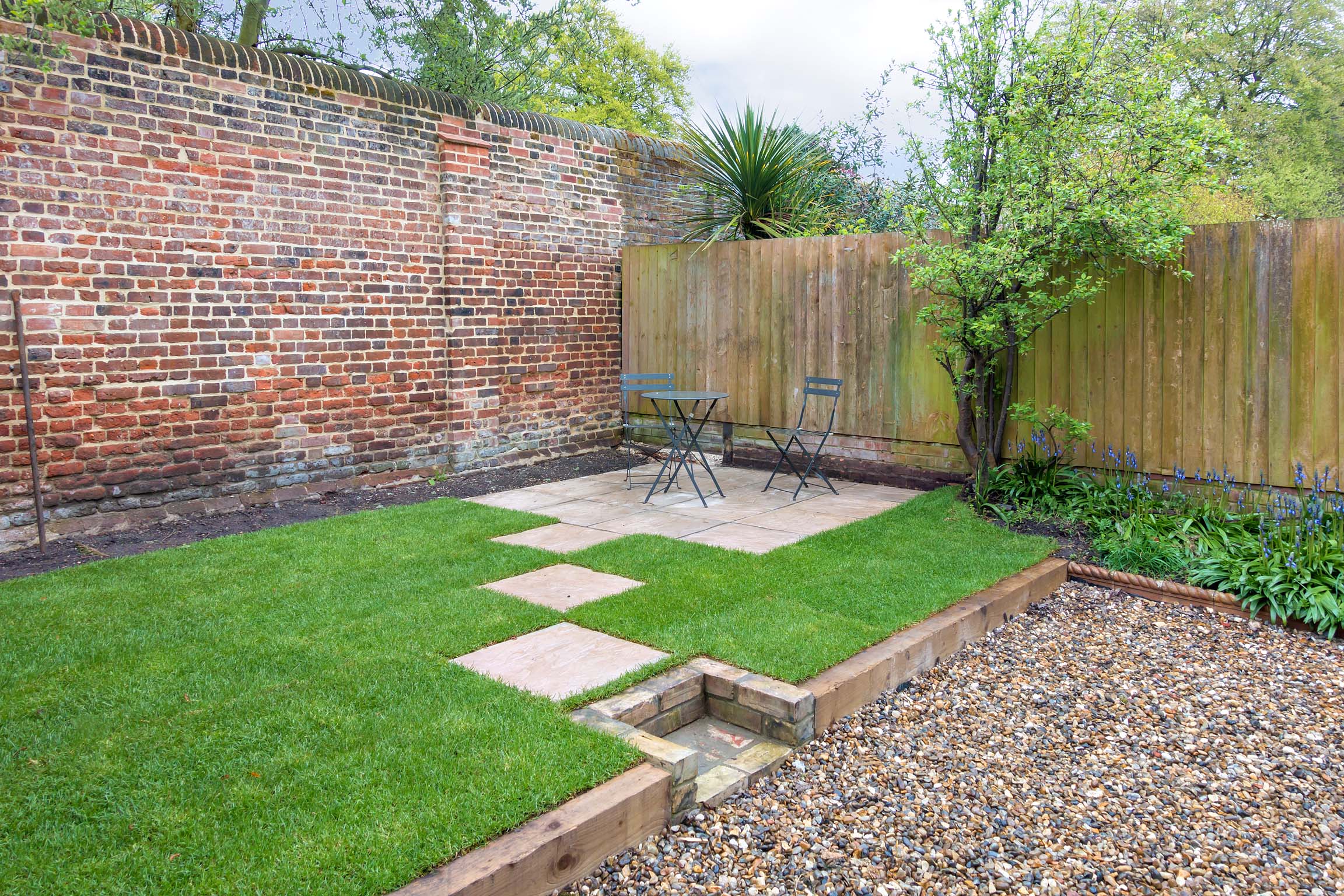 Grassy back garden with paved steps to patio area