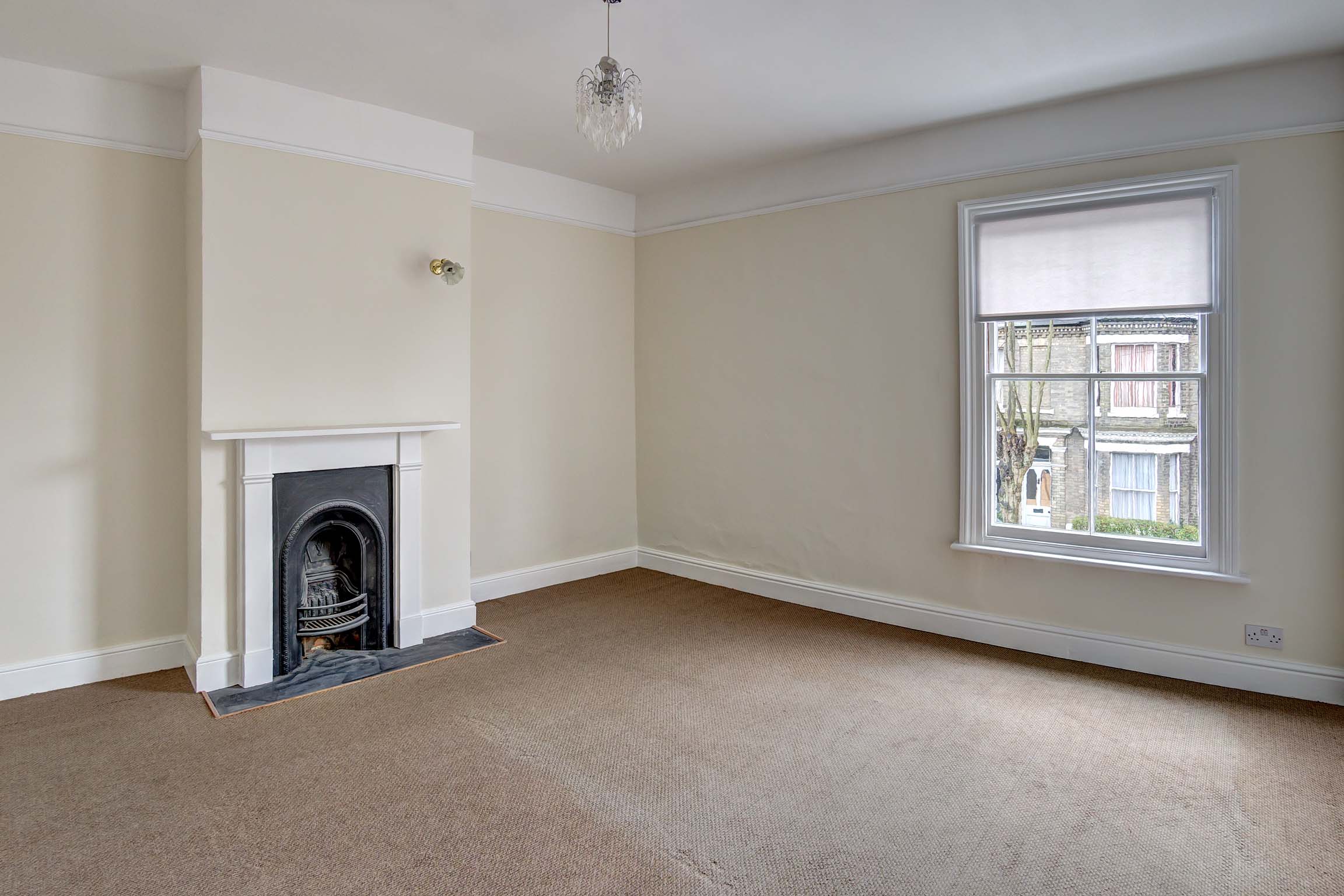 Double bedroom with cream walls, light carpet, and period fireplace.