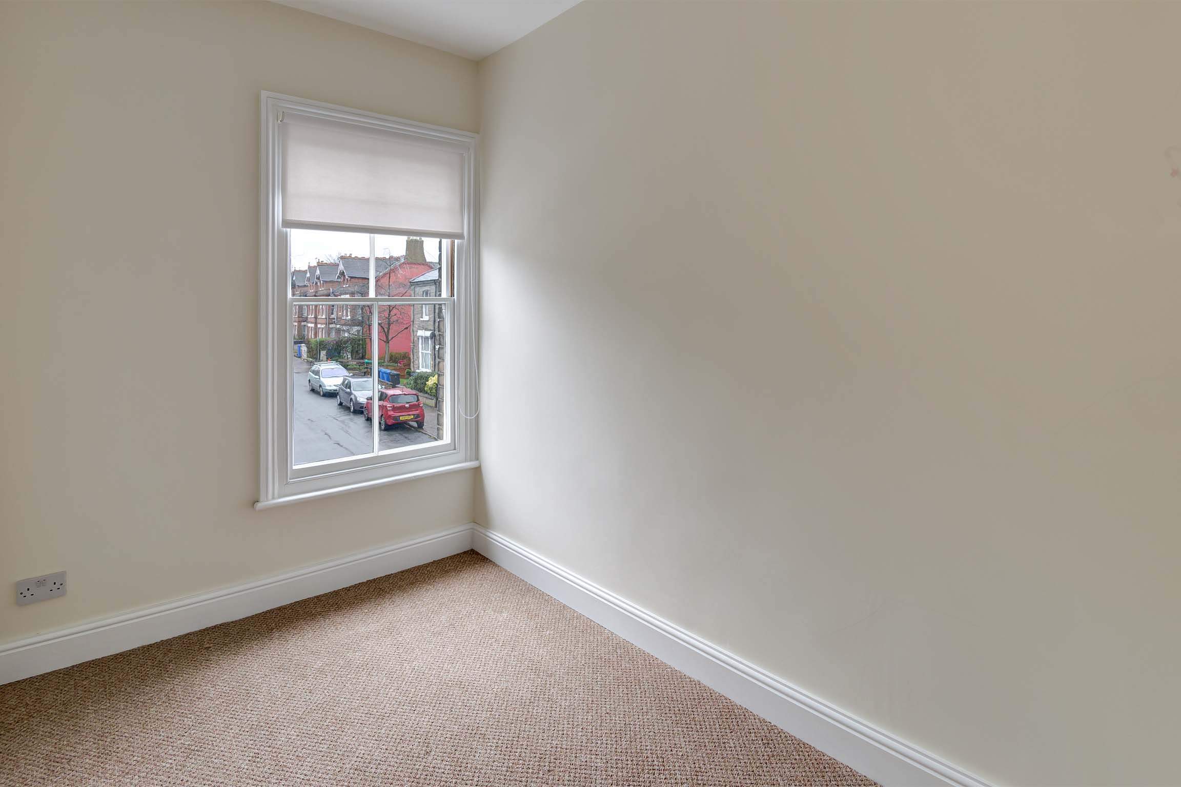 Single bedroom with cream walls and light carpet.
