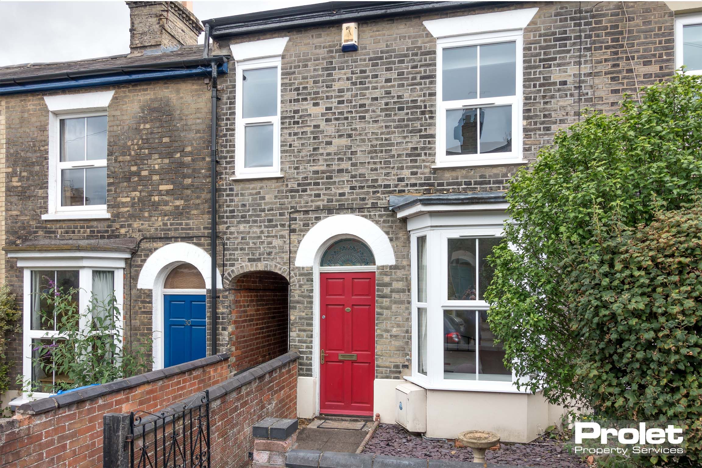 Terraced brick house with red door.
