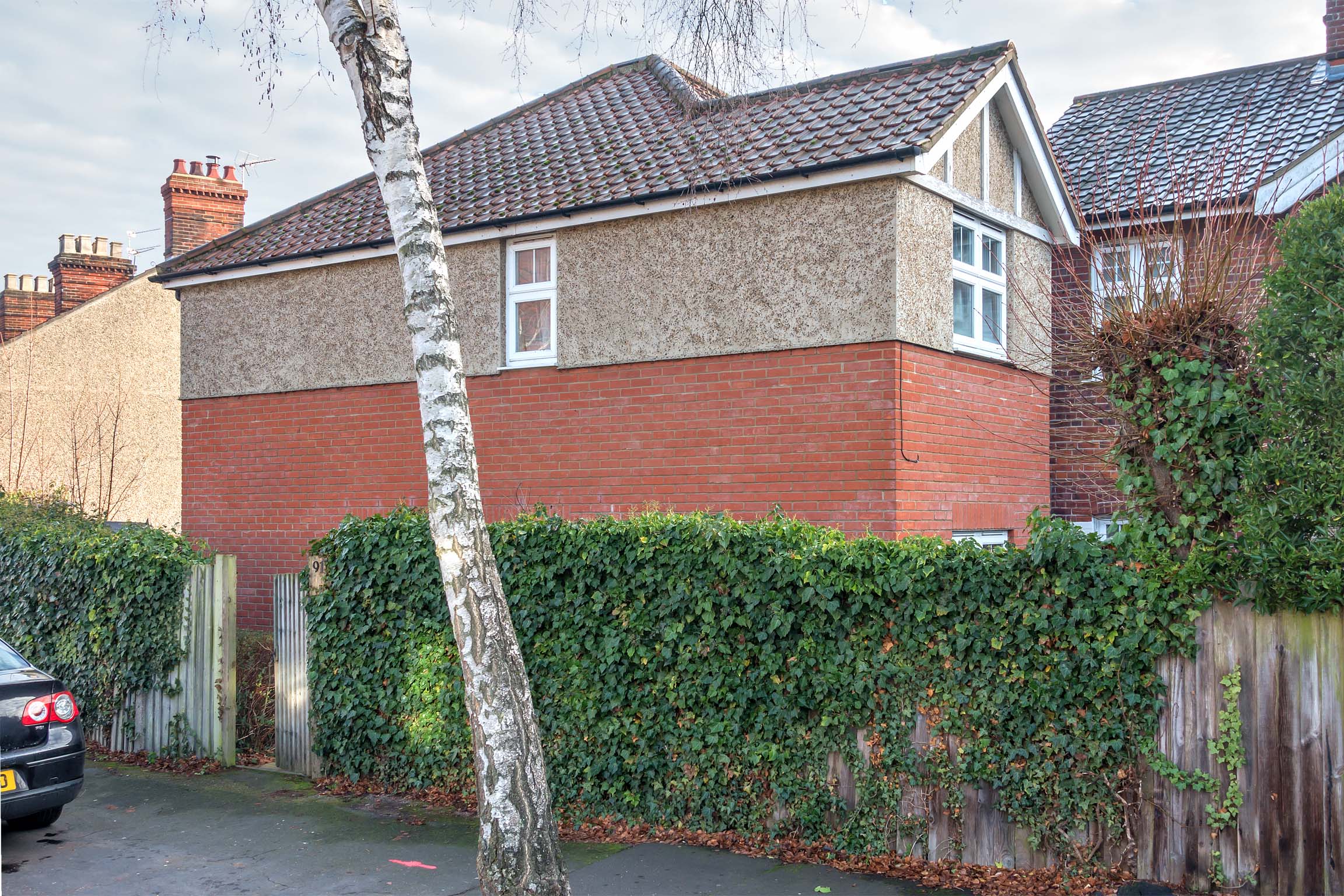 Brick semi-detached house with hedge infront