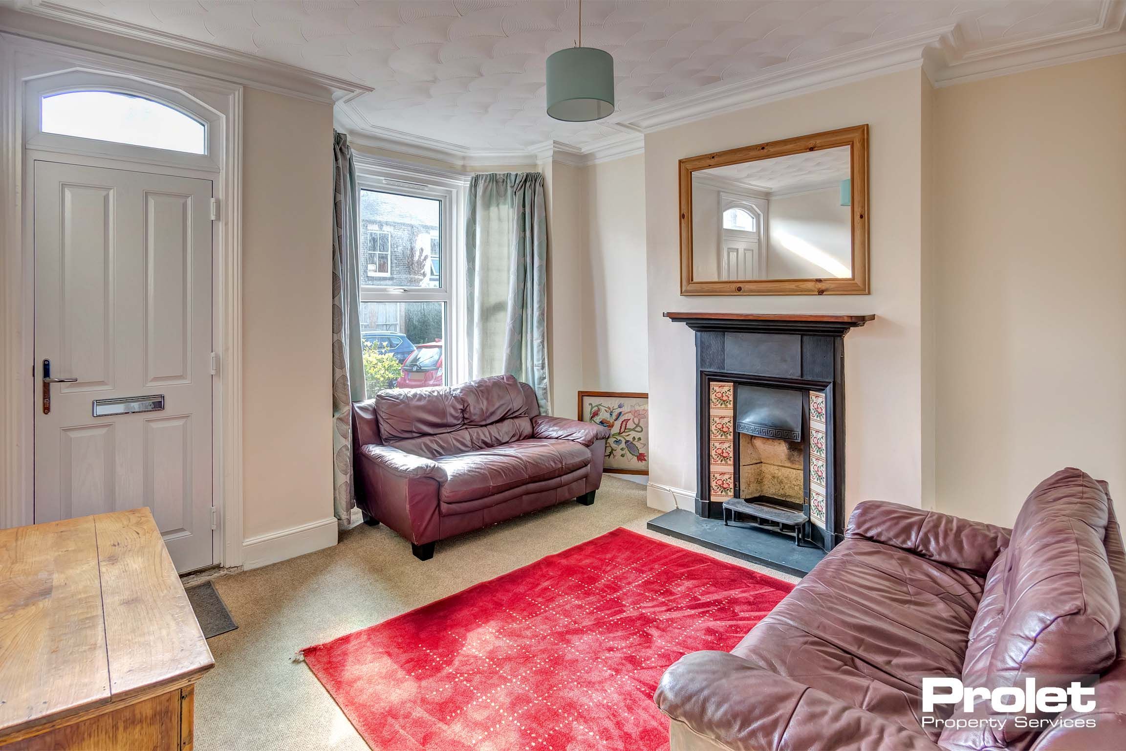 Living room with sofas, period fireplace, and front door entrance