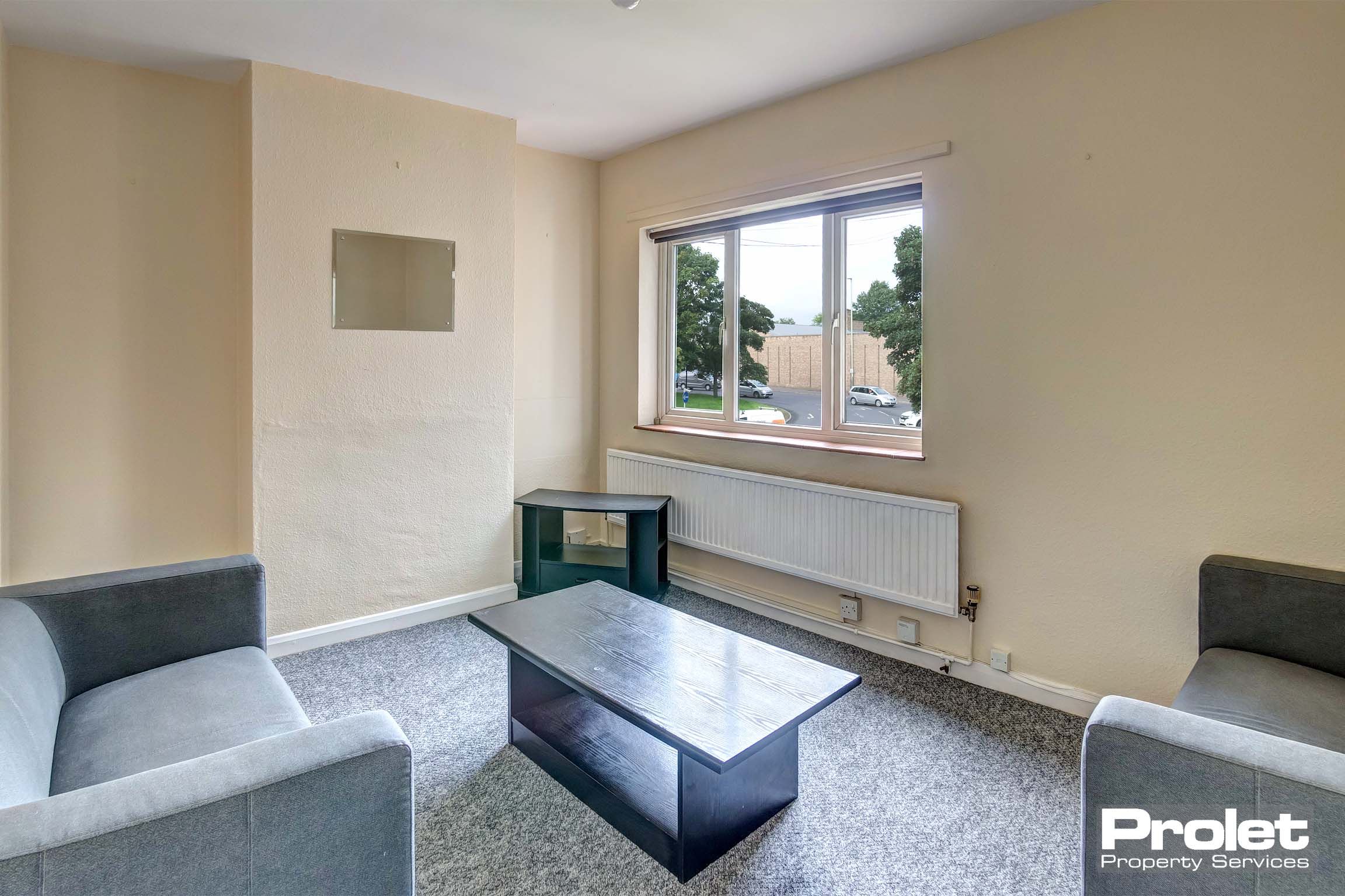 Living room with cream walls, grey carpet, and sofas