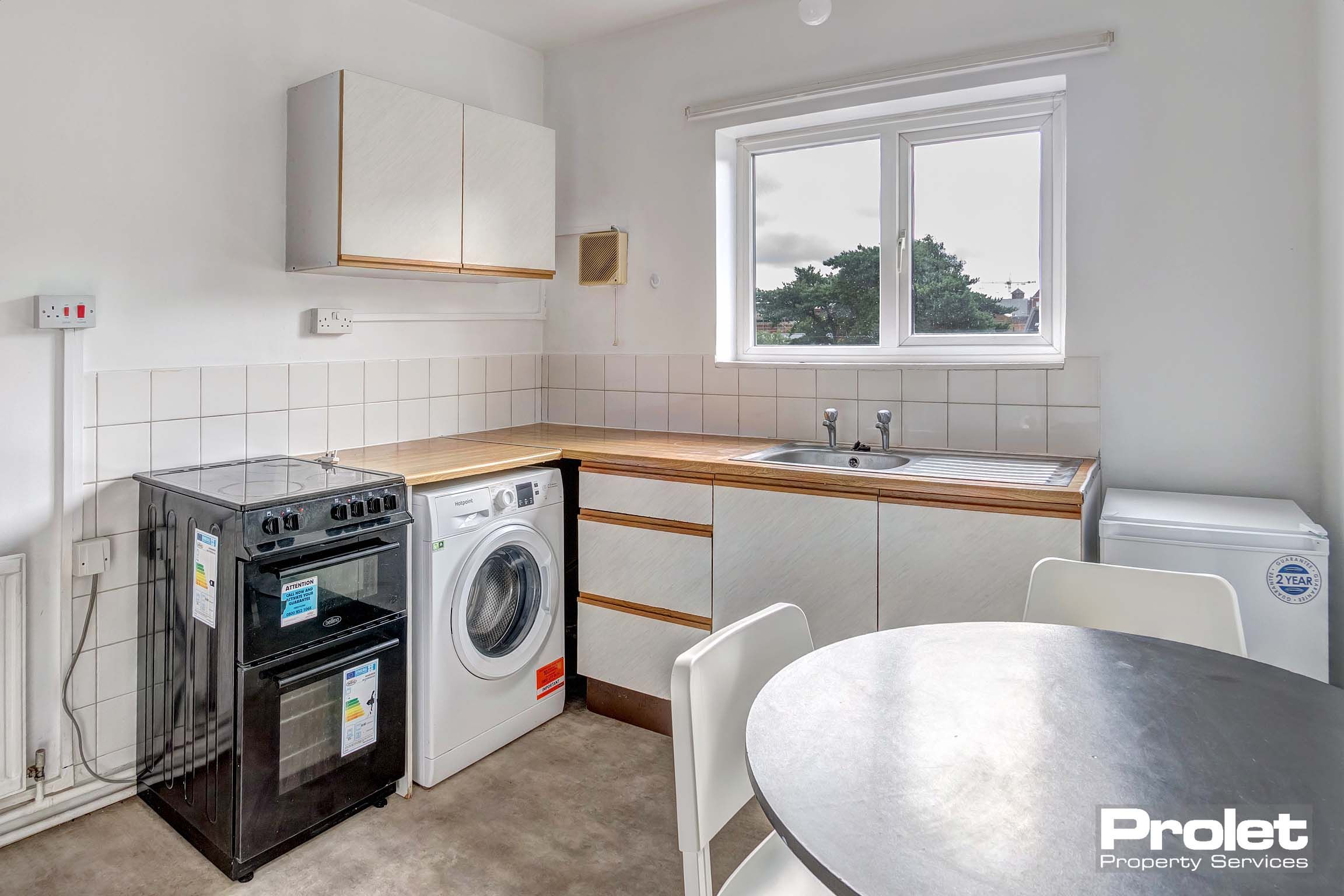 Kitchen with white goods, cabinets, and dining table set.