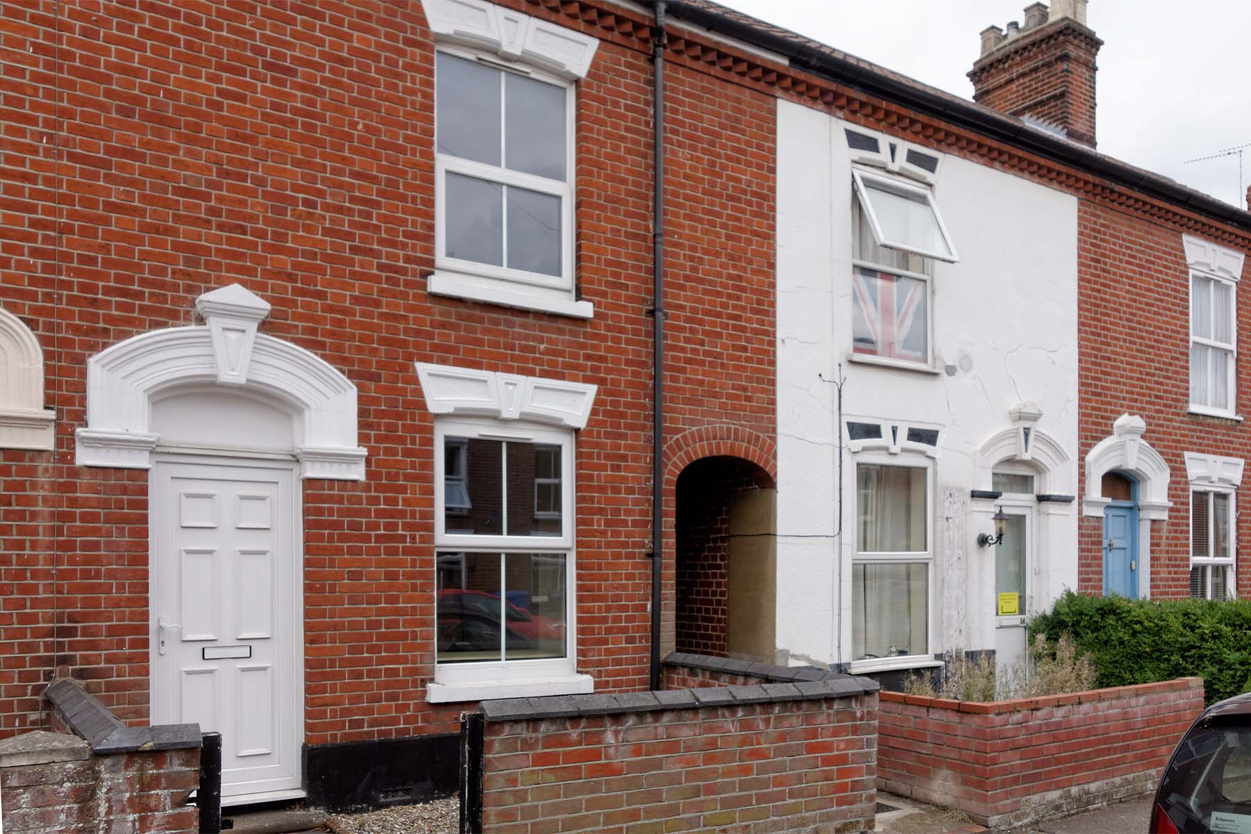 Red brick terraced house with white front door.