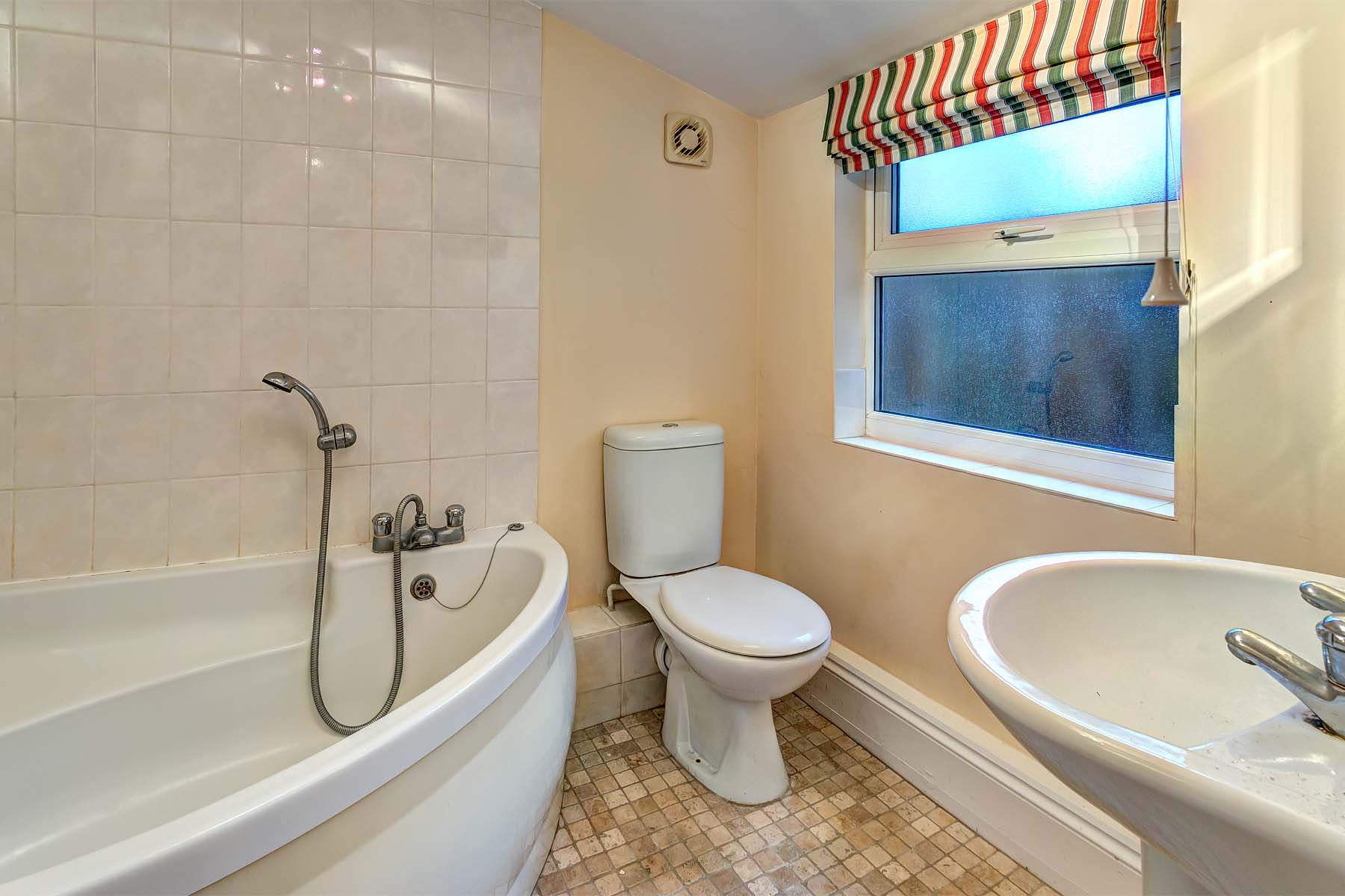Magnolia walls with vinyl flooring and white bathroom suite and corner bath with shower off taps.