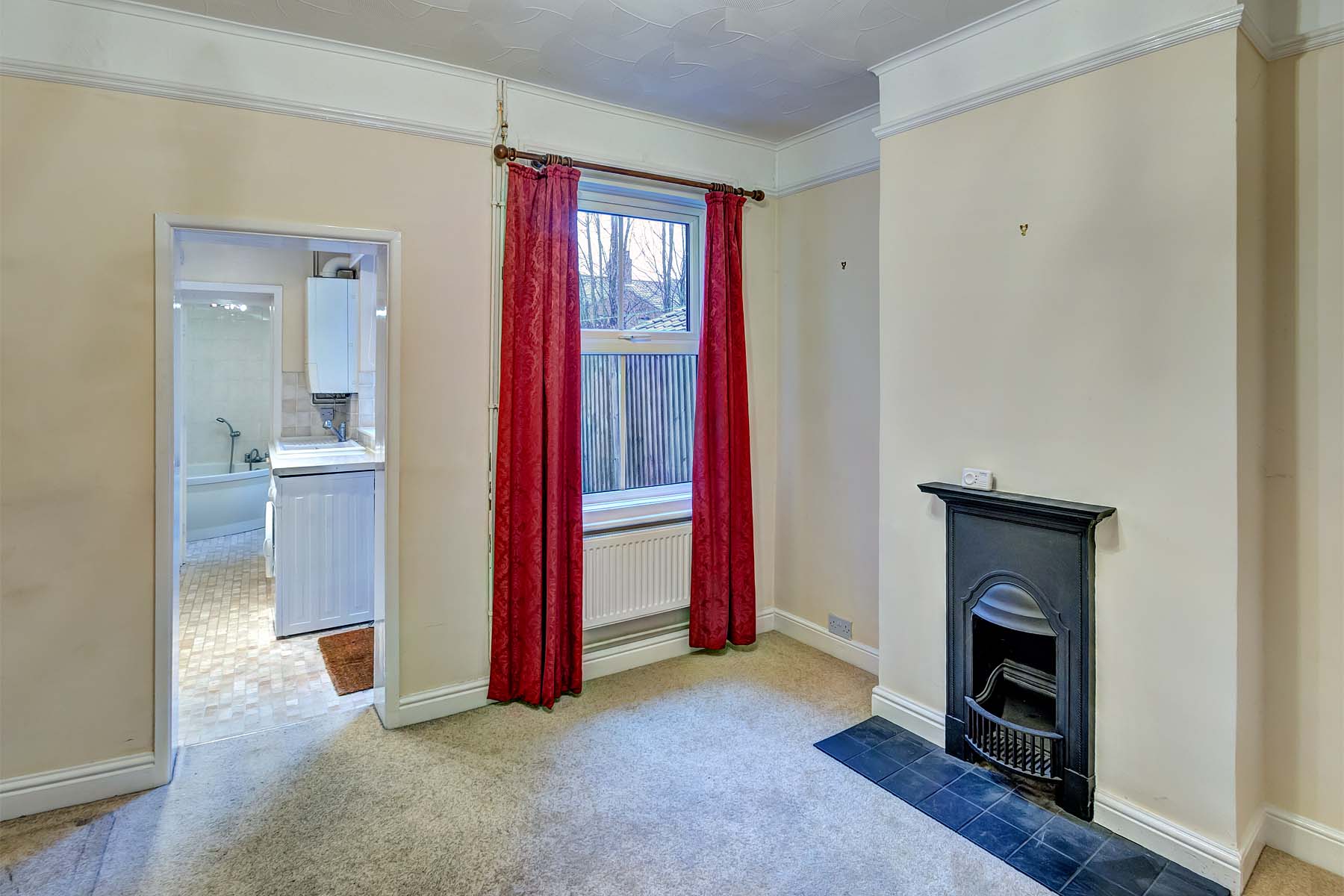 Cream carpet, magnolia walls & red curtains with feature fireplace