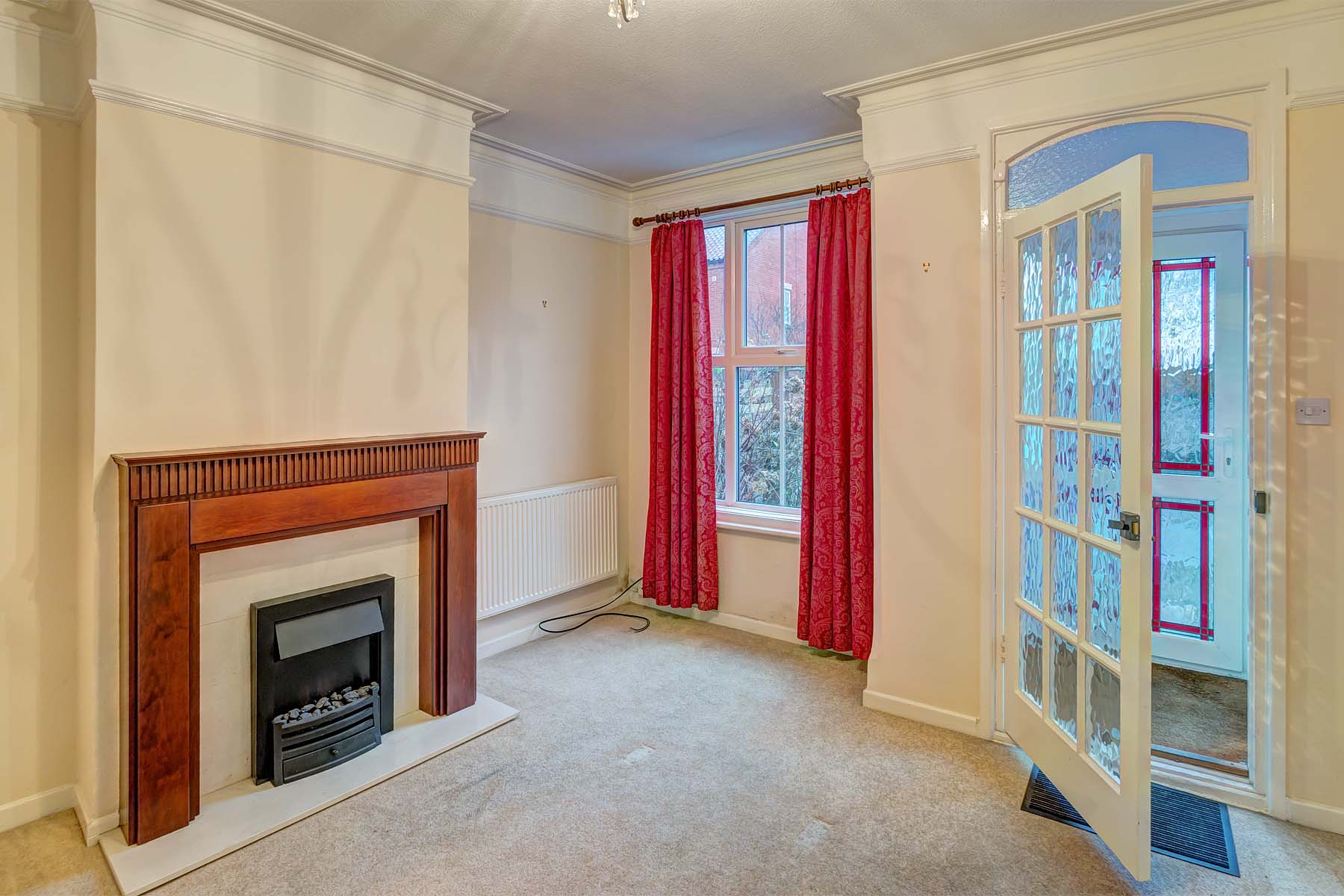 Cream carpet, magnolia walls & red curtains with feature fireplace