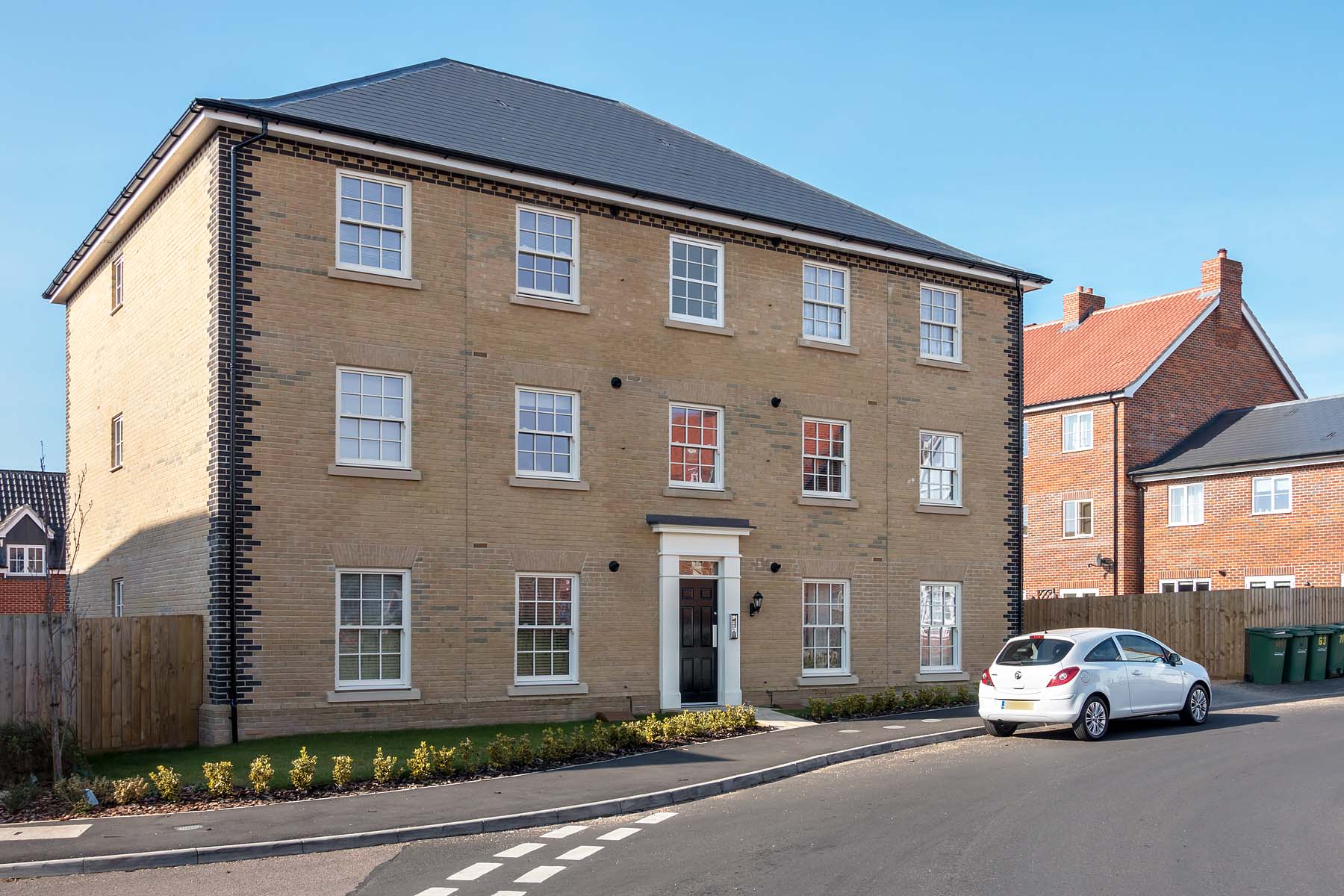 Beige brick apartment building with hedges