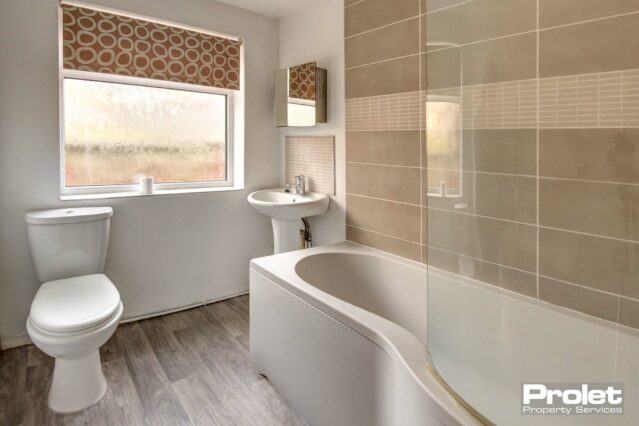 Bathroom with shower over bath, sink, and toilet.