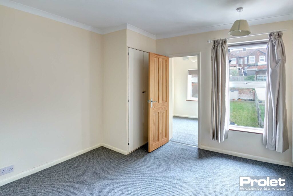 Double bedroom with cream walls and grey carpet, leading to study
