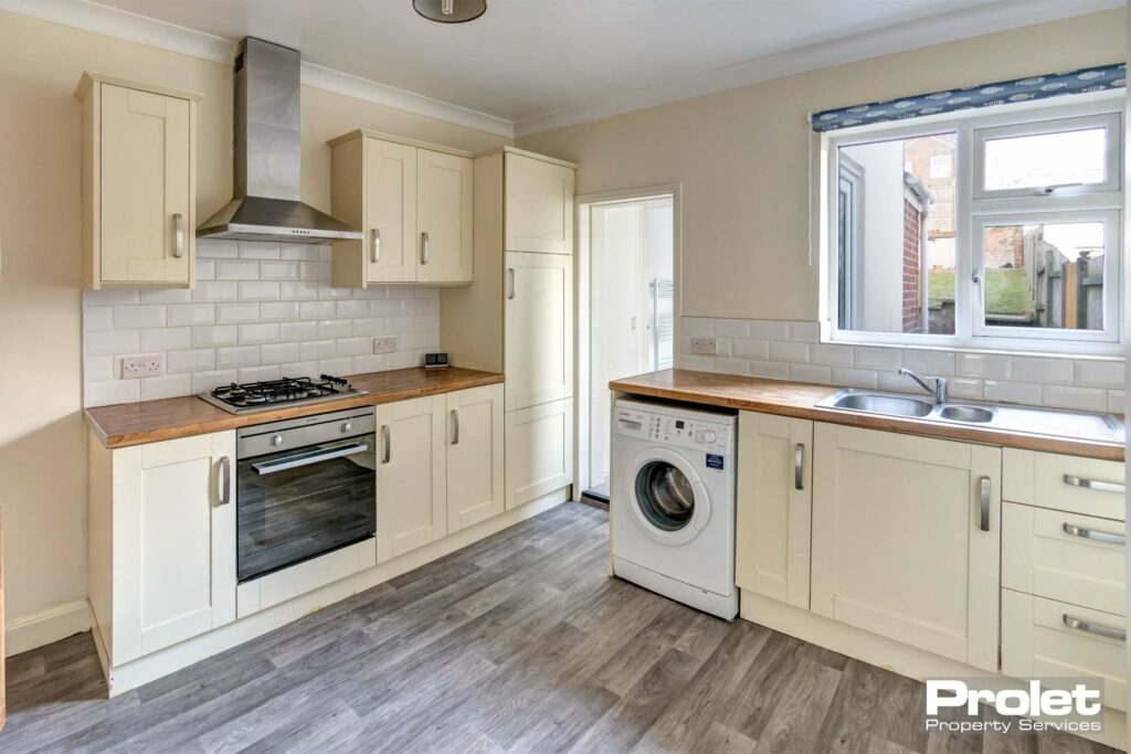 Kitchen with cream cabinets, and wood effect worktops. Oven and washing machine