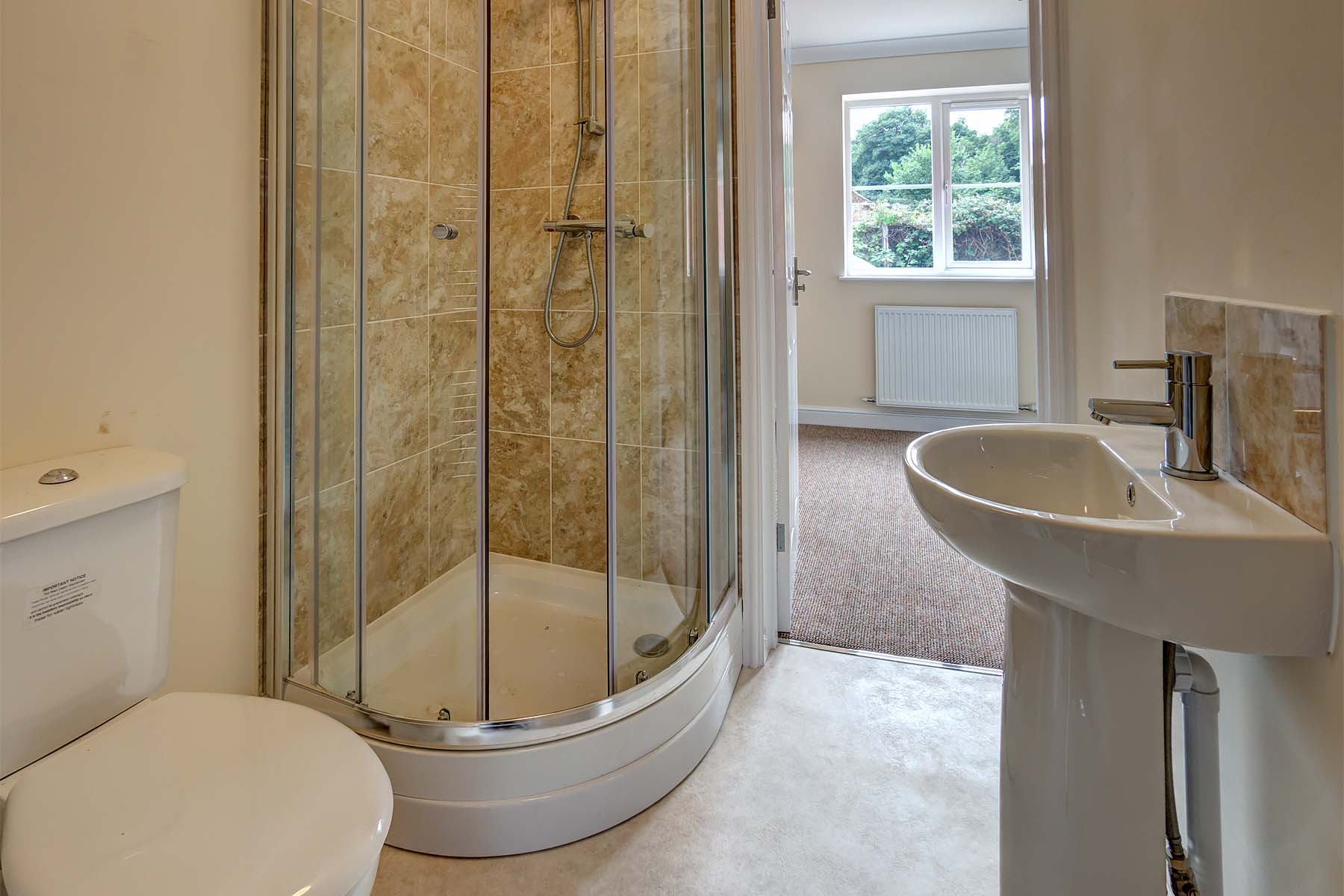 Tiled bathroom with sink, toilet, and shower cubicle