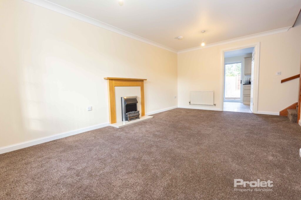 Large lounge with brown carpet, cream walls, and fireplace