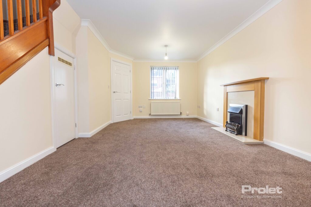 Large lounge with brown carpet, cream walls, and fireplace