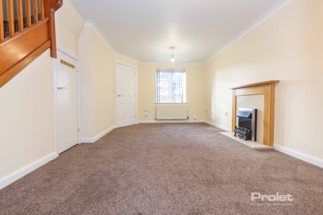 Large lounge with brown carpet, cream walls, and fireplace